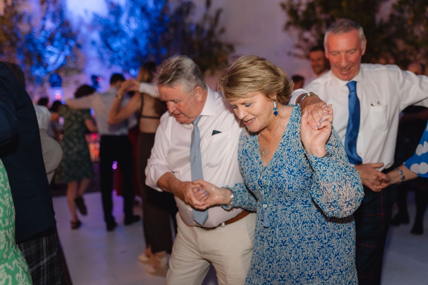 Evening wedding celebration with guests dancing under warm lighting.