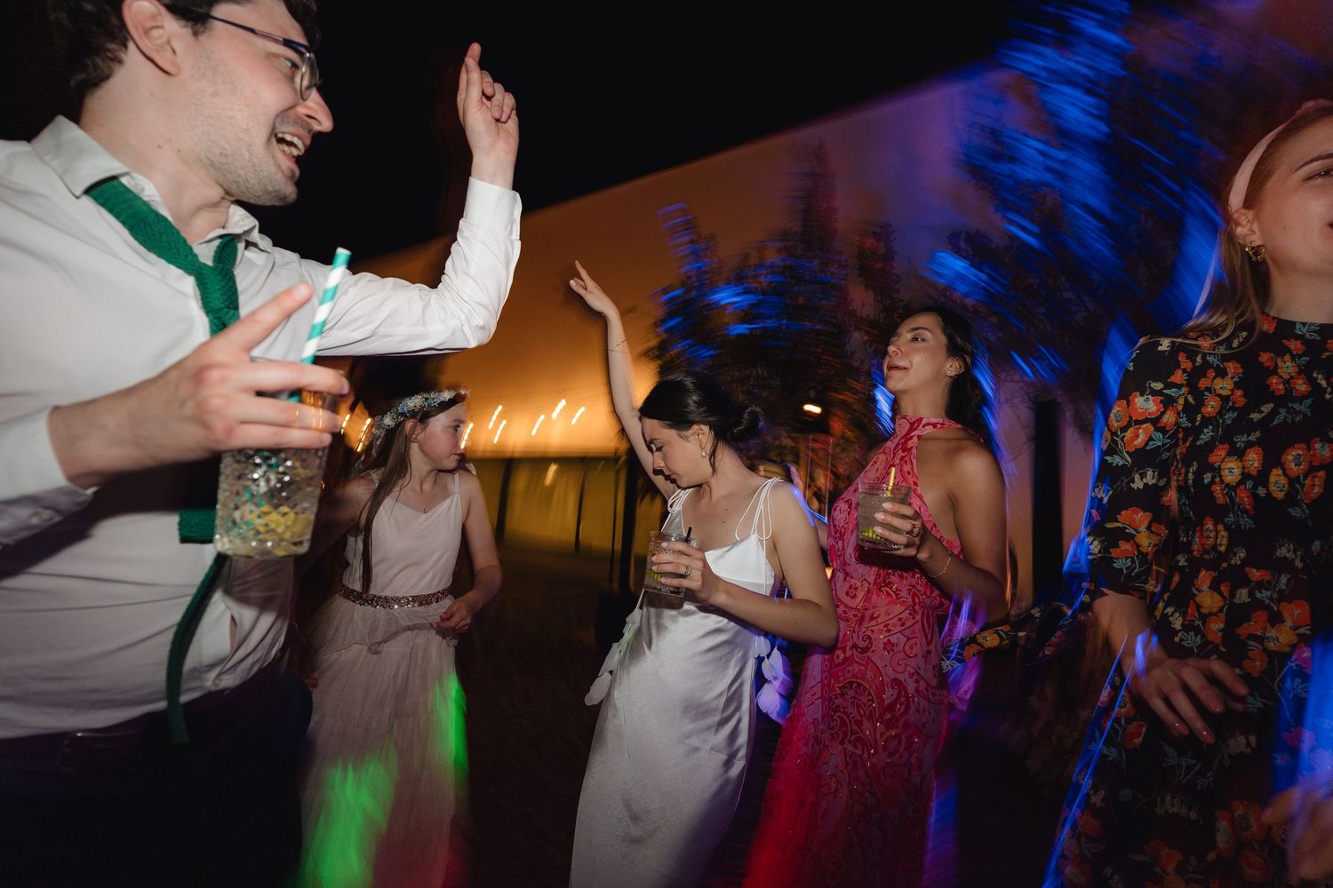 Dancers enjoying themselves at a lively indoor celebration with blue lighting.