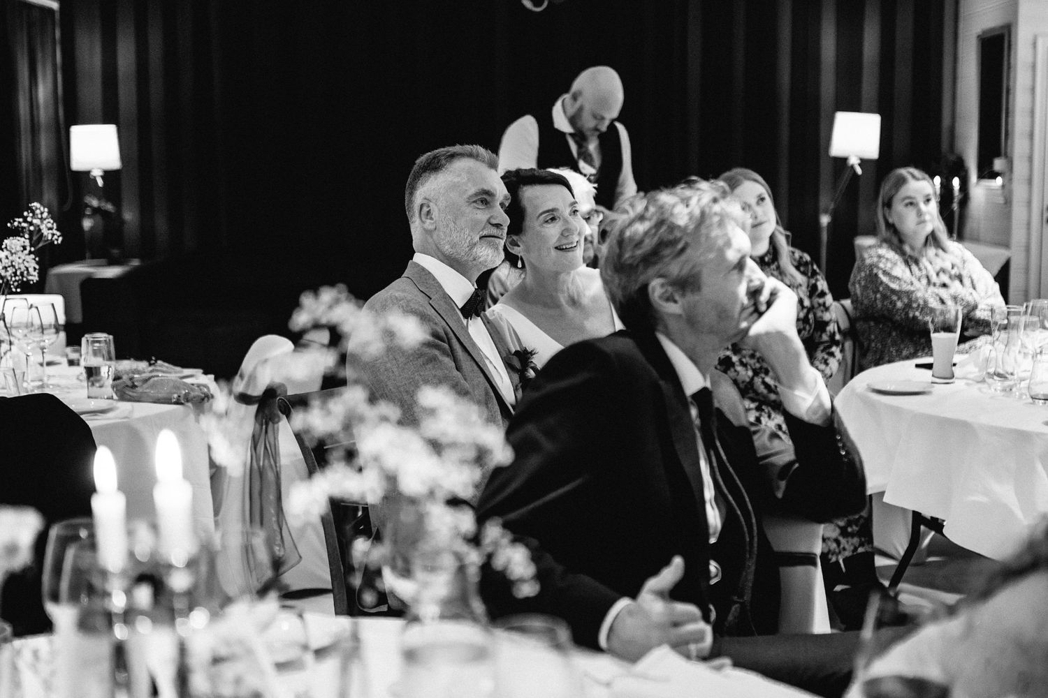 Candid black and white photos of wedding guests dining and socializing at an evening reception.