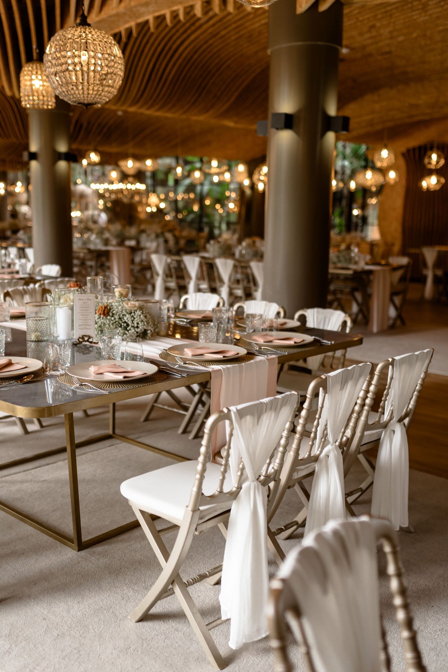 Modern wedding reception tables with silver chairs and elegant place settings in a luxurious venue.