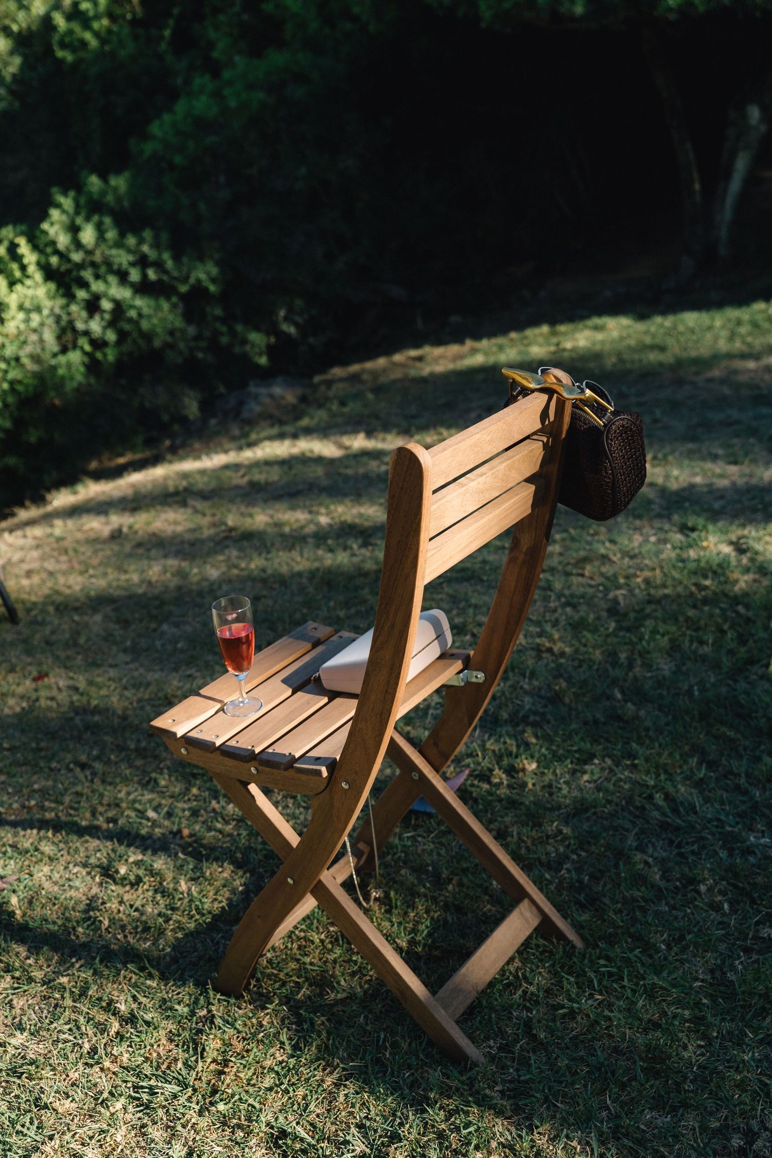 Wooden folding chairs arranged on grass in dappled sunlight.