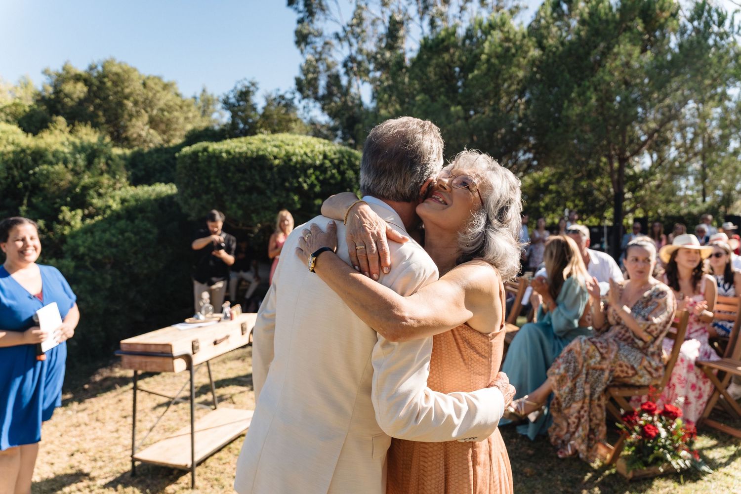 Wedding celebration captured on a sunny hillside with guests mingling.