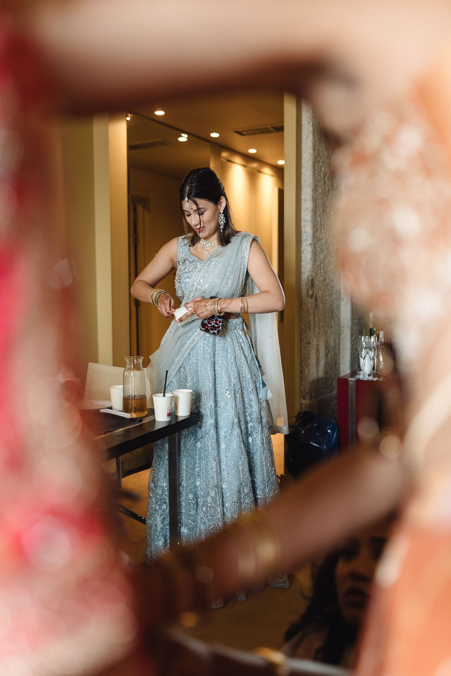 Elegant woman in a pale blue lace dress getting ready in a hotel room.