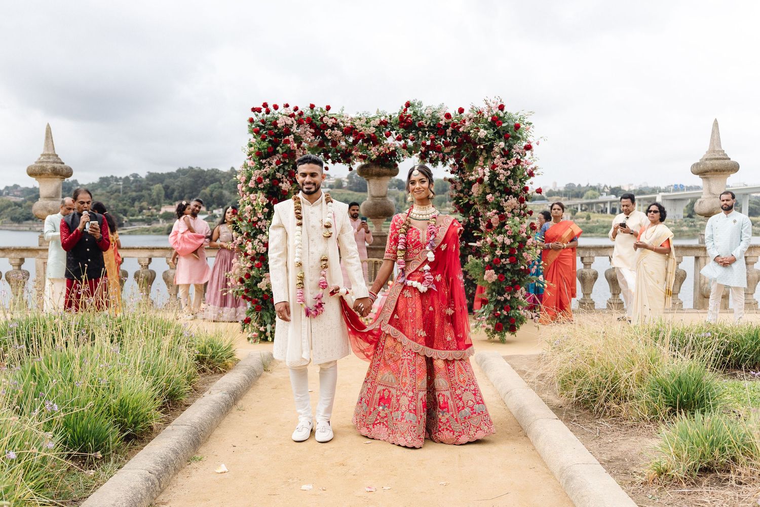 Panoramic view of outdoor wedding venue with floral arch and guests gathering.