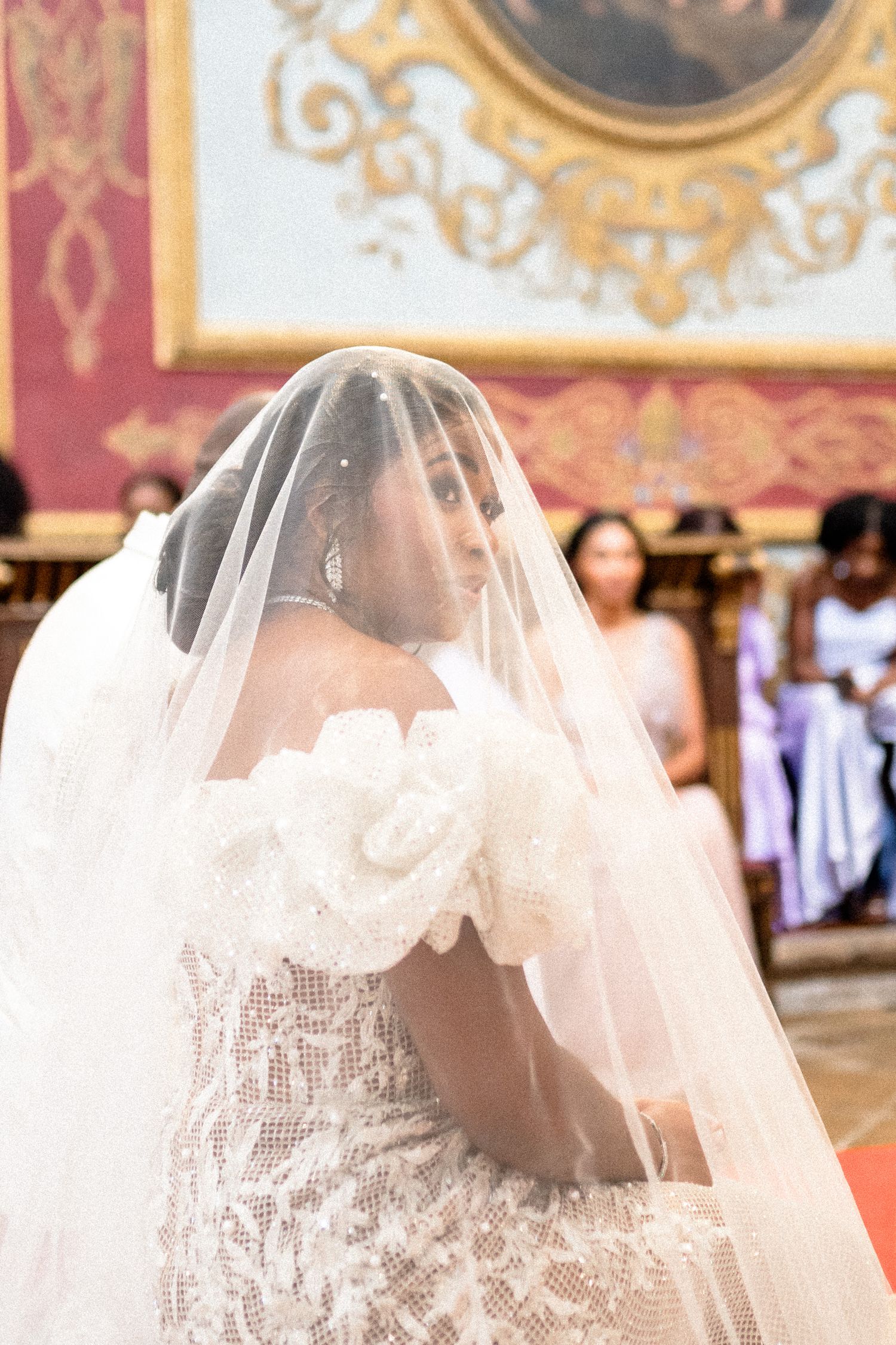 A close-up view of a delicate lace wedding veil with intricate details against an ornate background.