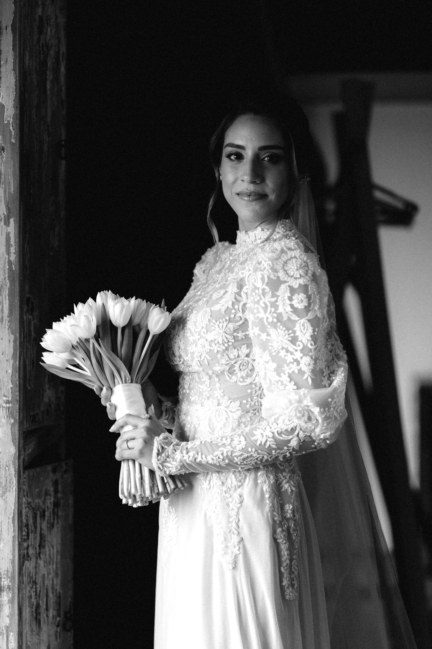 Bridal portrait featuring a delicate lace wedding dress and white floral bouquet.