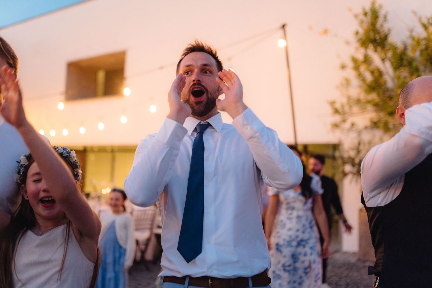 Guests cheering and celebrating enthusiastically at an outdoor evening event.