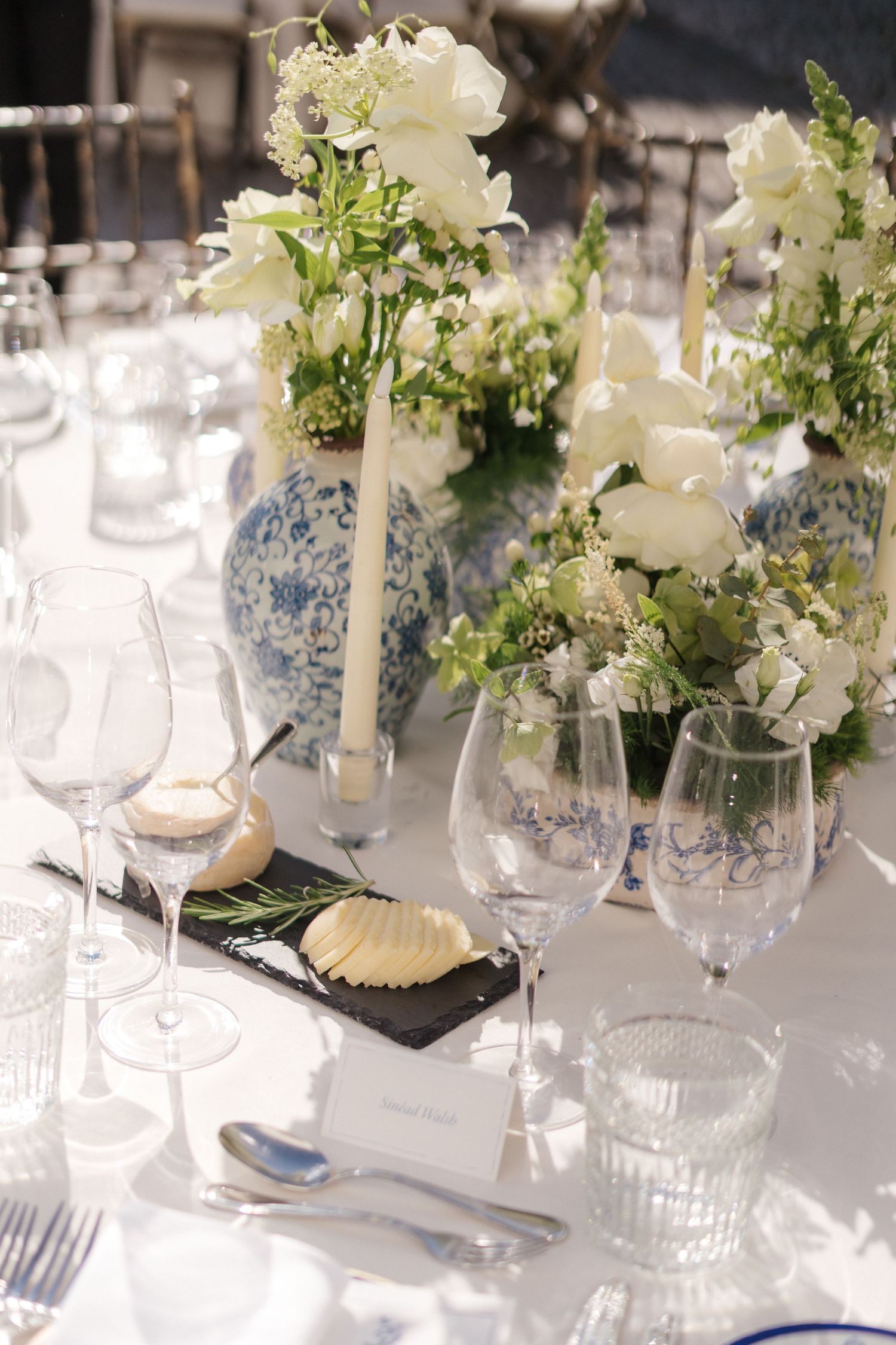 Formal table setting with white floral arrangements in blue and white porcelain vases.
