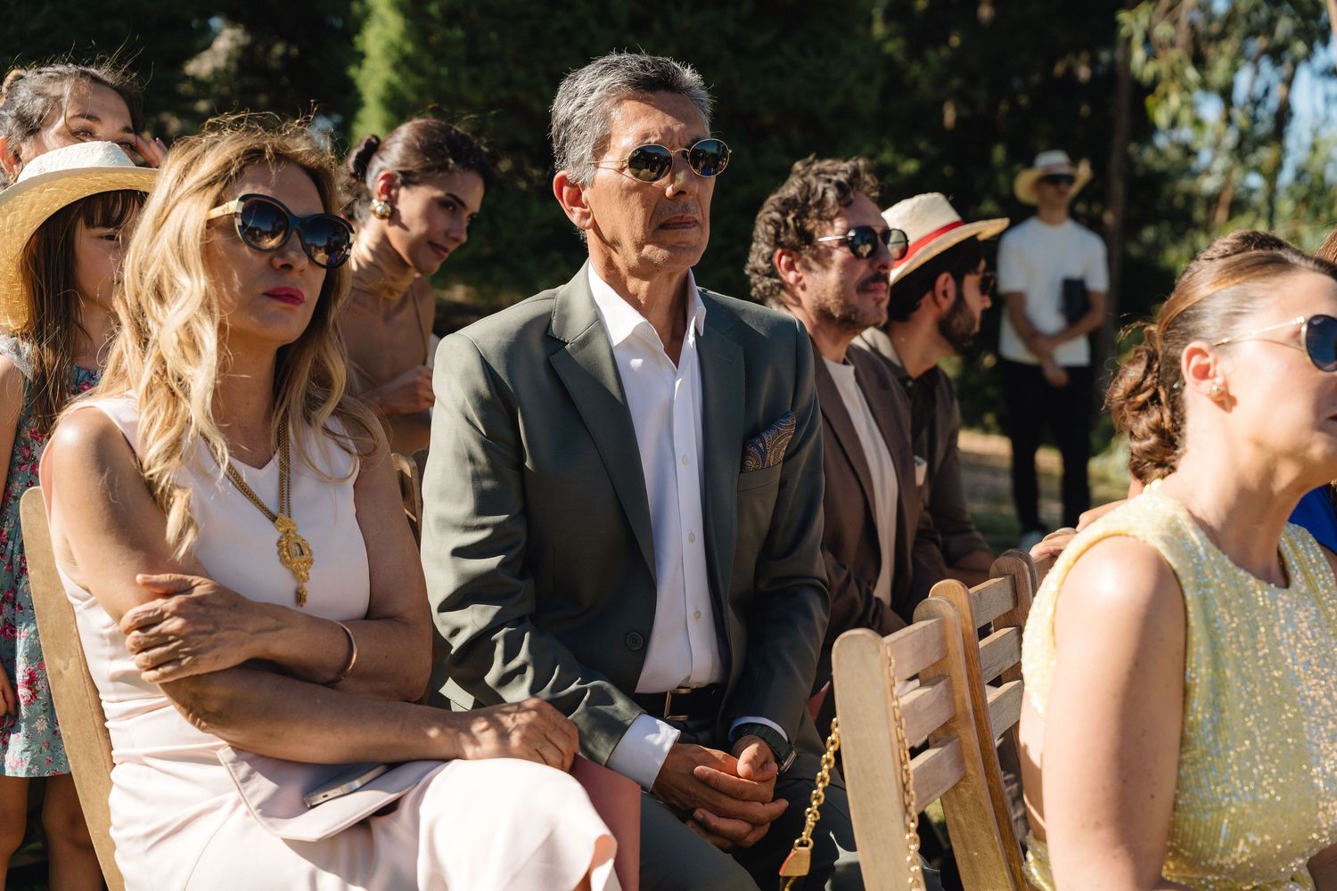 Wedding guests mingle during outdoor reception under natural lighting.