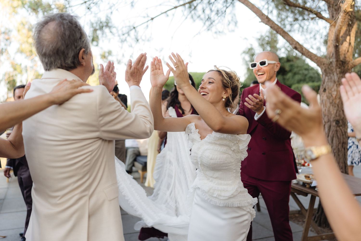 Wedding party dances and celebrates during an outdoor reception at sunset.