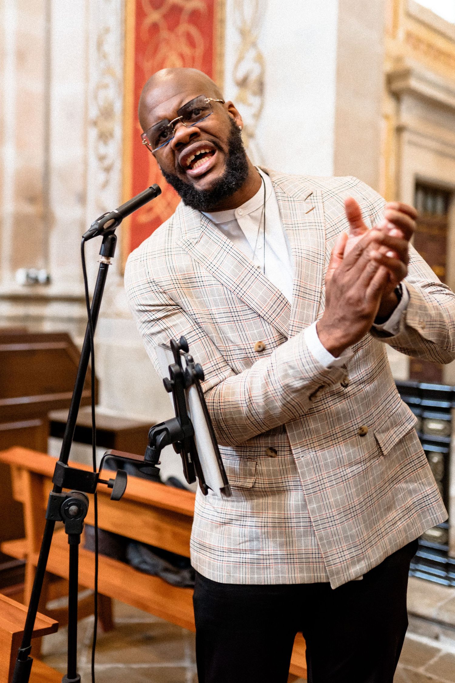 Person in plaid suit jacket gesturing expressively during a wedding celebration.