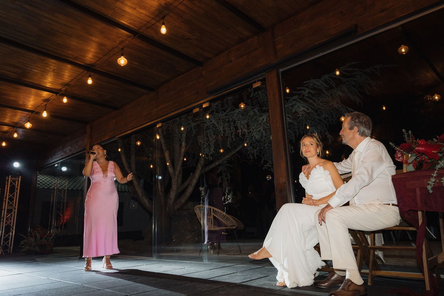 A wedding reception scene with a performer singing while the newlyweds watch from their seats.