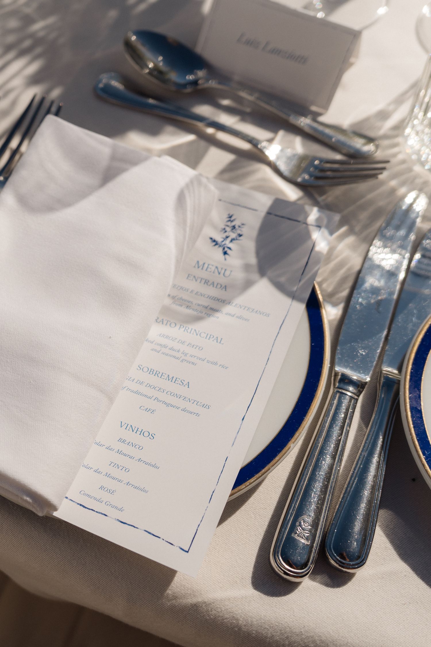 Wedding menu card with blue details placed beside silverware and white napkin.