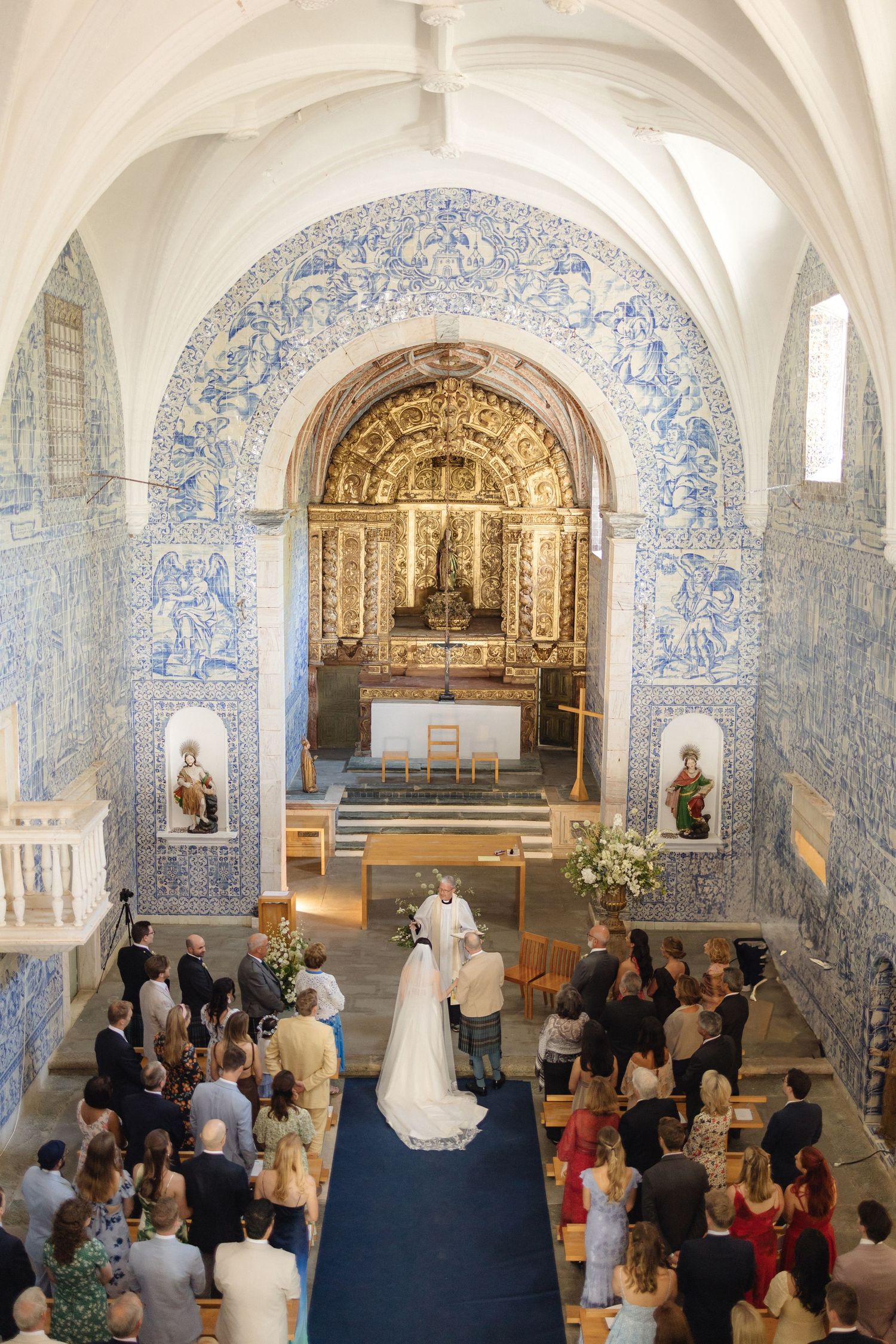 Overhead view of a wedding ceremony in a Portuguese chapel with vaulted ceilings and blue tile walls.