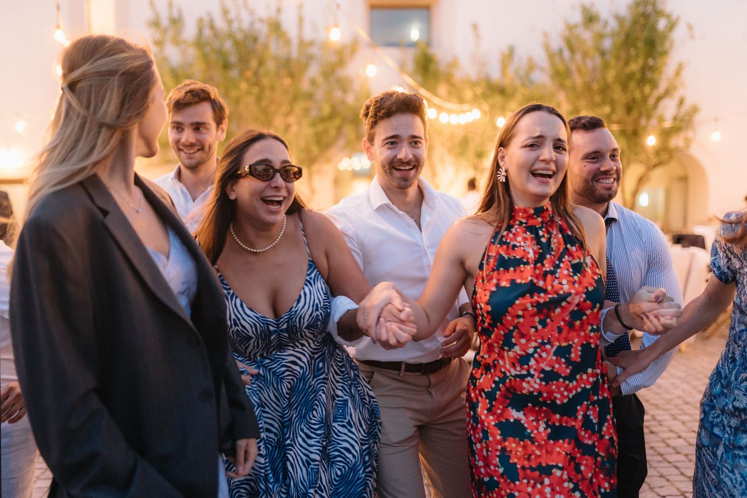 Wedding guests celebrating and dancing together at an outdoor evening reception.