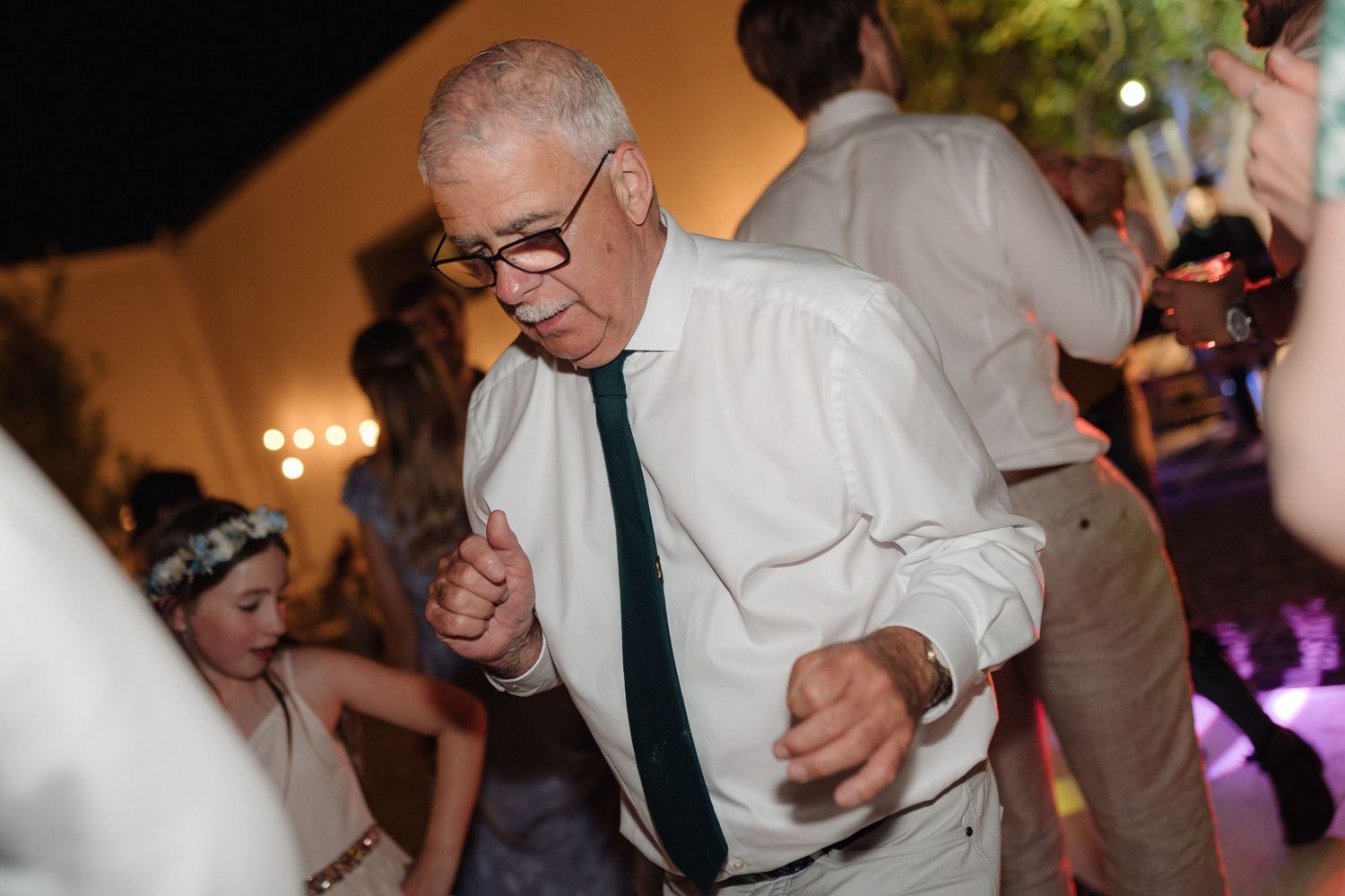 Party guests dancing energetically at a wedding reception with dramatic lighting effects.