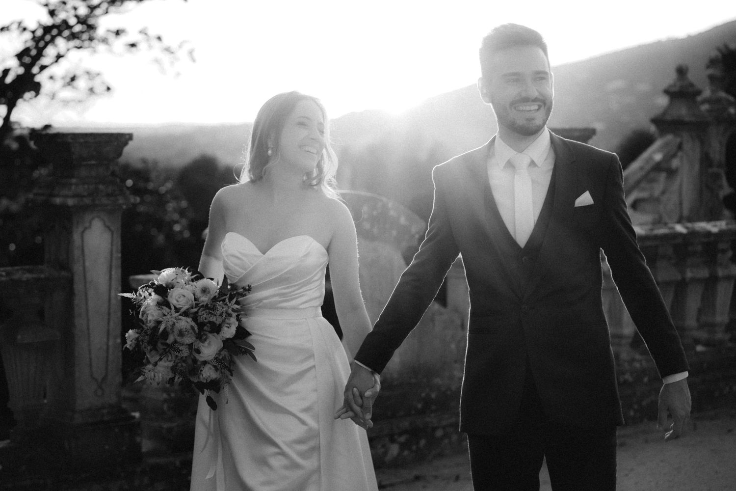 Black and white silhouette of couple in wedding attire during sunset.