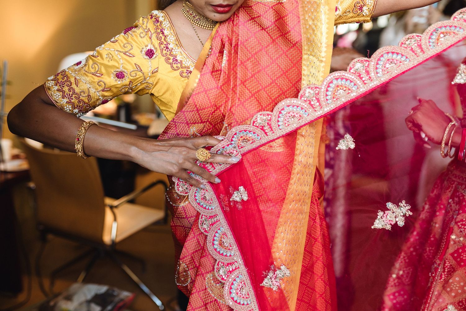 Detail shot of intricate embroidery on a red Indian wedding lehenga.