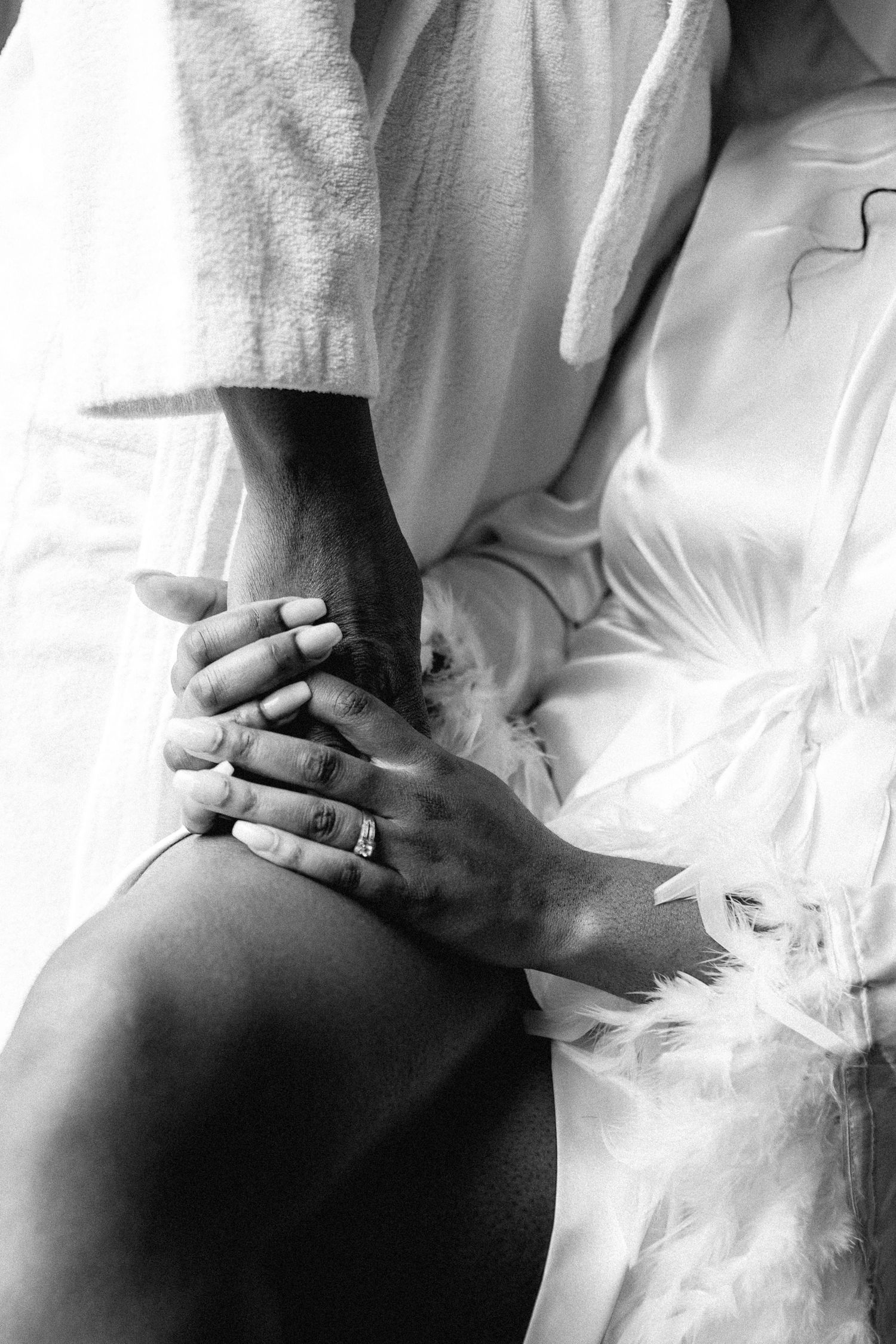 Black and white artistic photo showing hands with rings against white fabric.