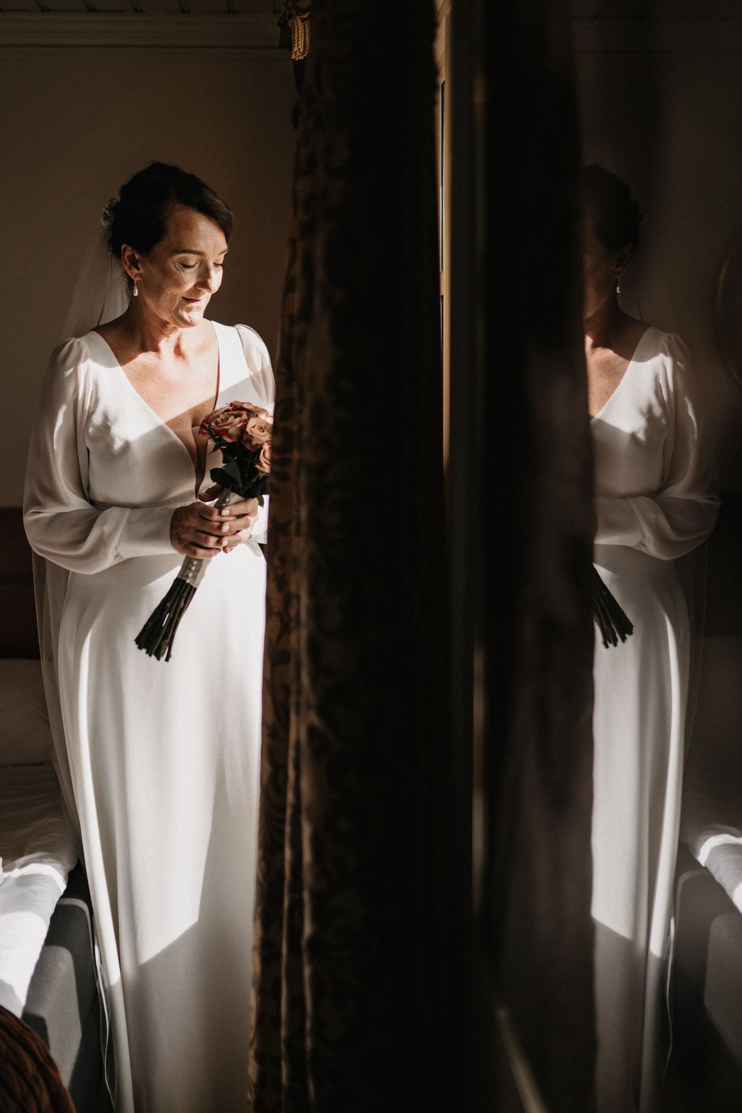 Dramatic lighting illuminates a person in a flowing white dress against dark shadows.