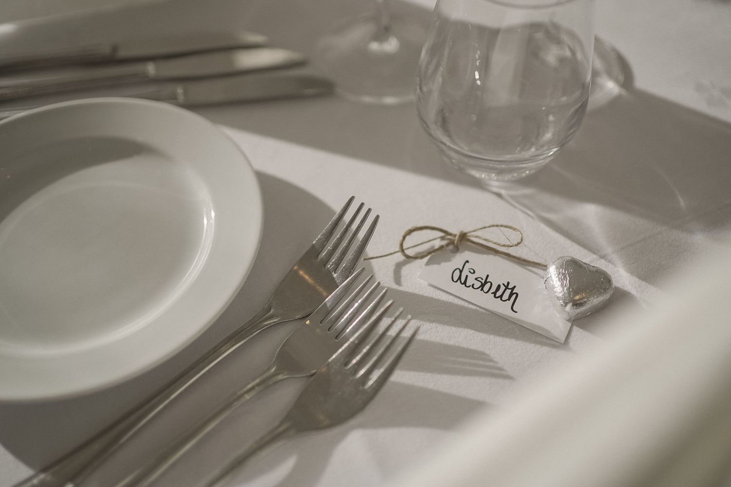 Elegant place settings with wine glasses and name cards on white tablecloths.