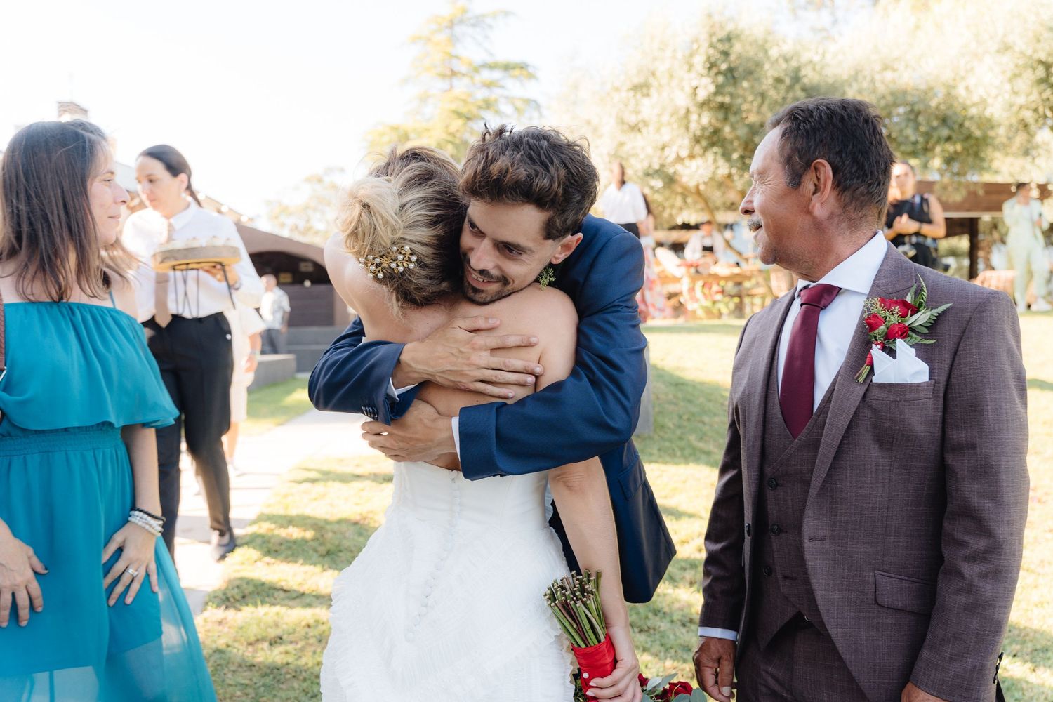Guests share warm hugs during an outdoor wedding reception.