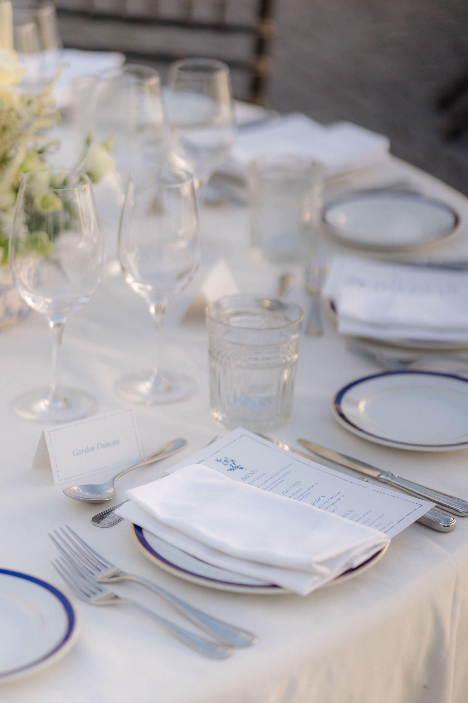 Elegant table settings with white linens, blue-rimmed plates, and crystal glassware.