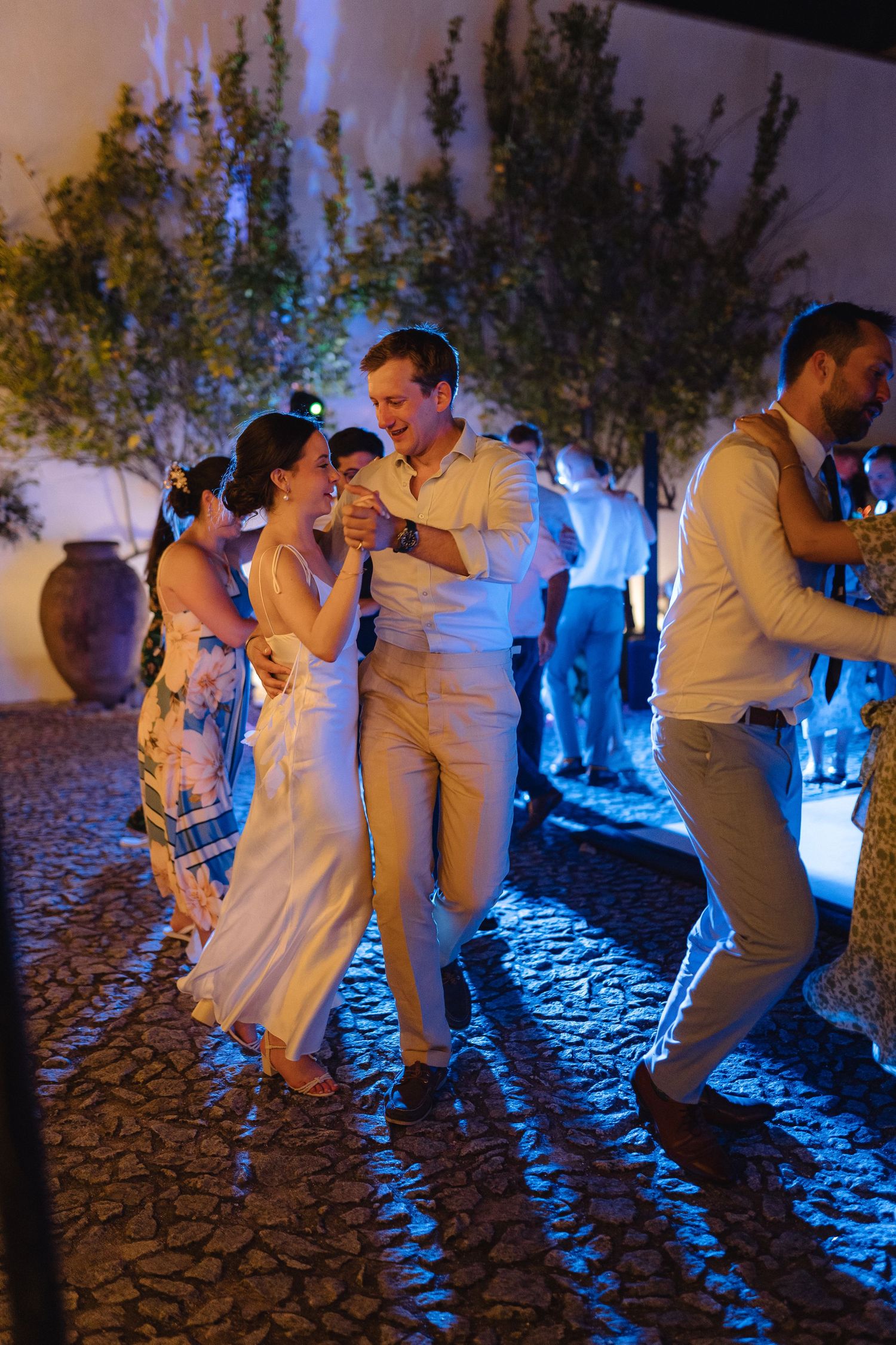 Couples dancing together at a wedding reception with dramatic blue lighting effects.