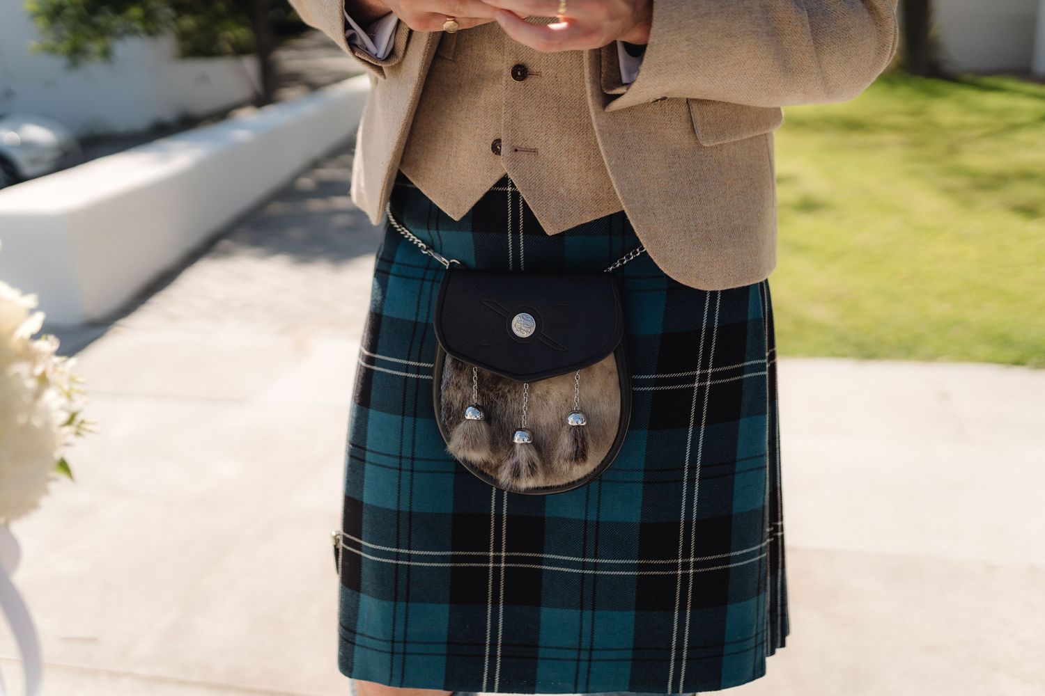 Close-up detail of a traditional Scottish kilt sporran in blue and green tartan pattern.