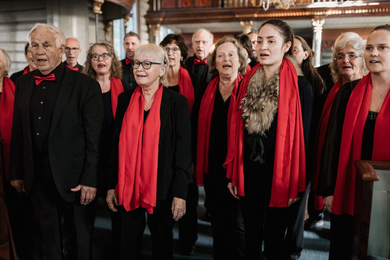 Choir members wearing red scarves perform during a formal event.