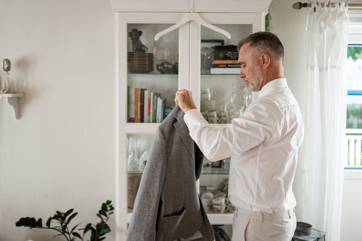 Person in white shirt adjusts artwork on a bright white wall in a modern interior space.