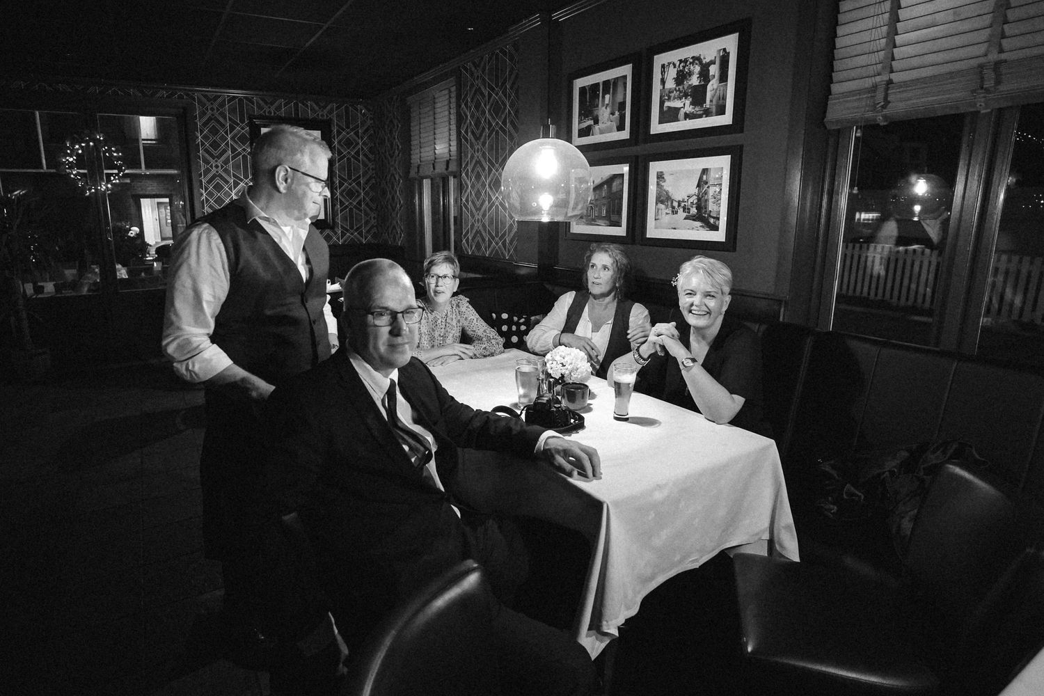 Black and white photos of an intimate restaurant dining setting with moody lighting.