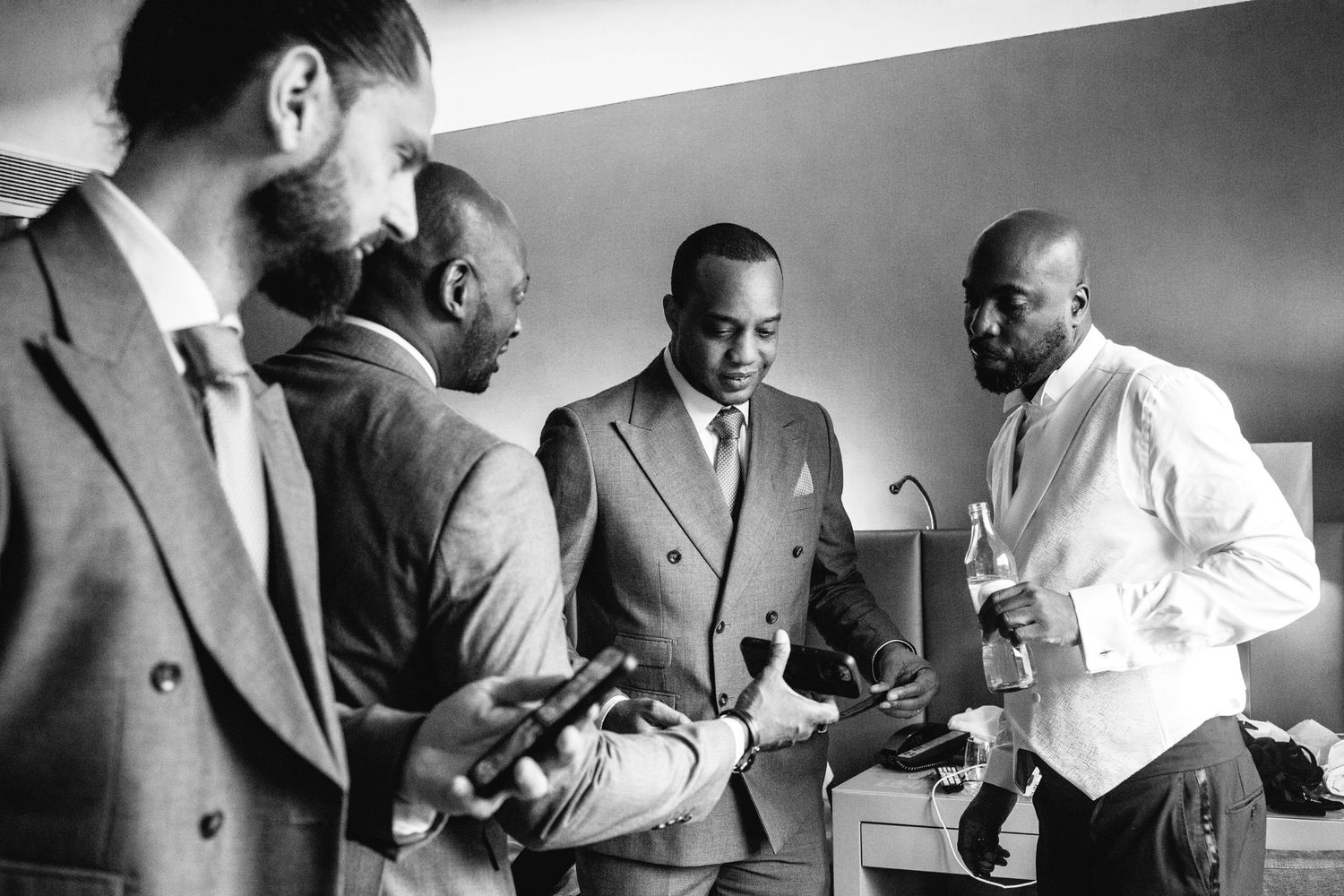 Groomsmen in suits gather together in a black and white photograph.