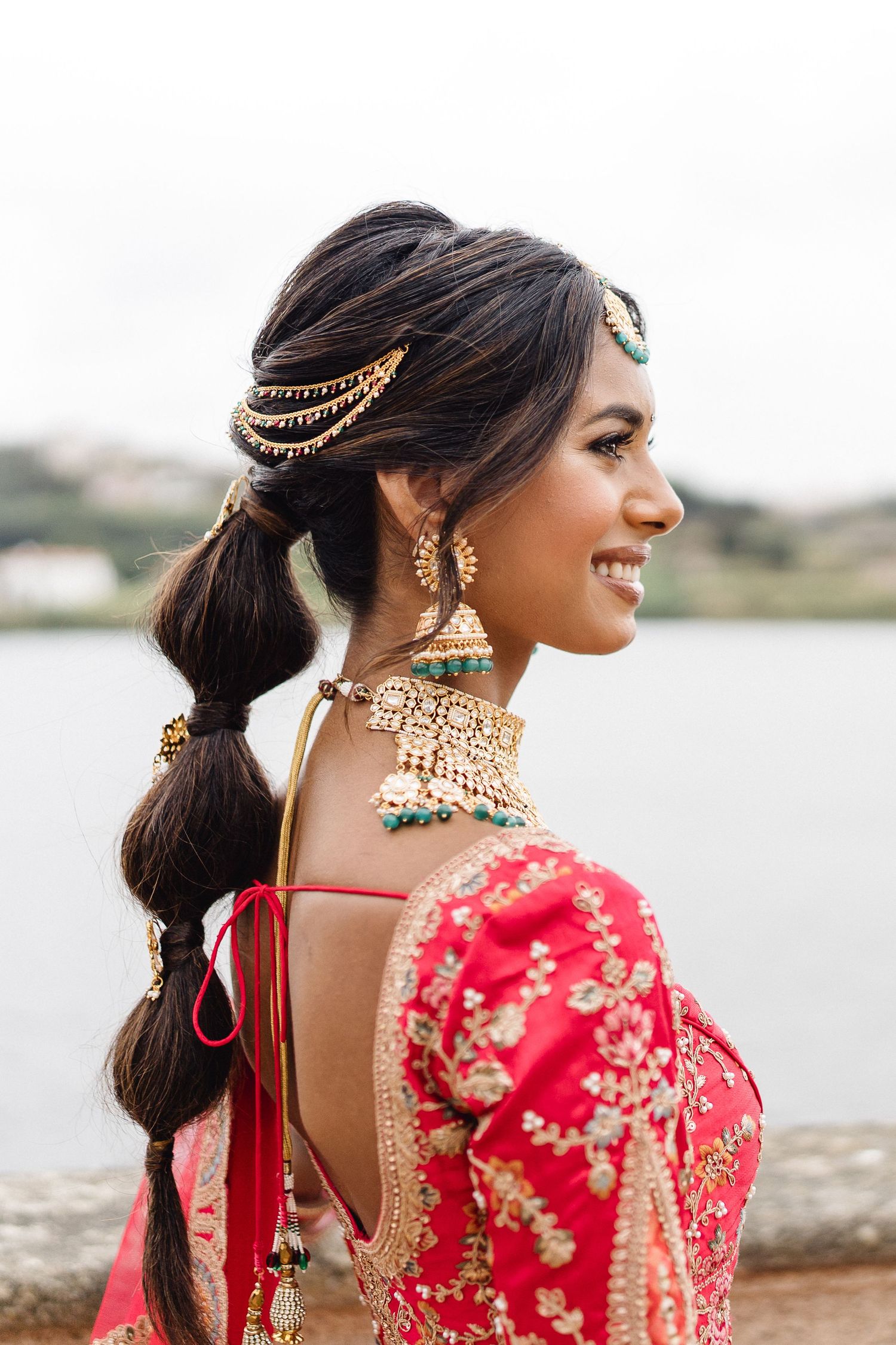 Side profile of traditional Indian bridal jewelry and hairstyle with gold accessories.