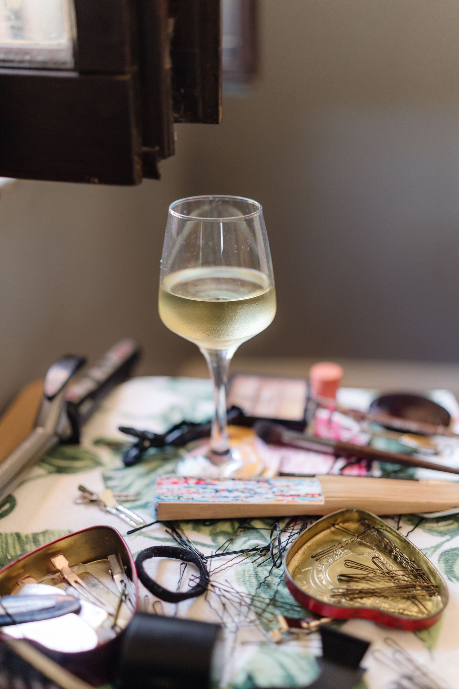 Glass of white wine with travel maps and accessories spread on a table.
