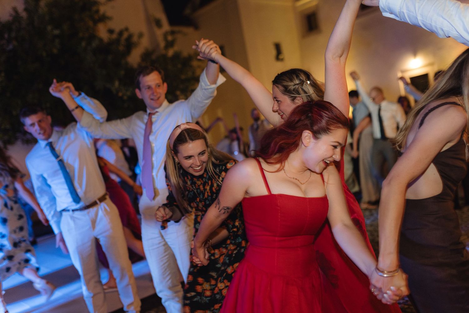 Wedding guests dancing and celebrating with colorful dresses on the dance floor.
