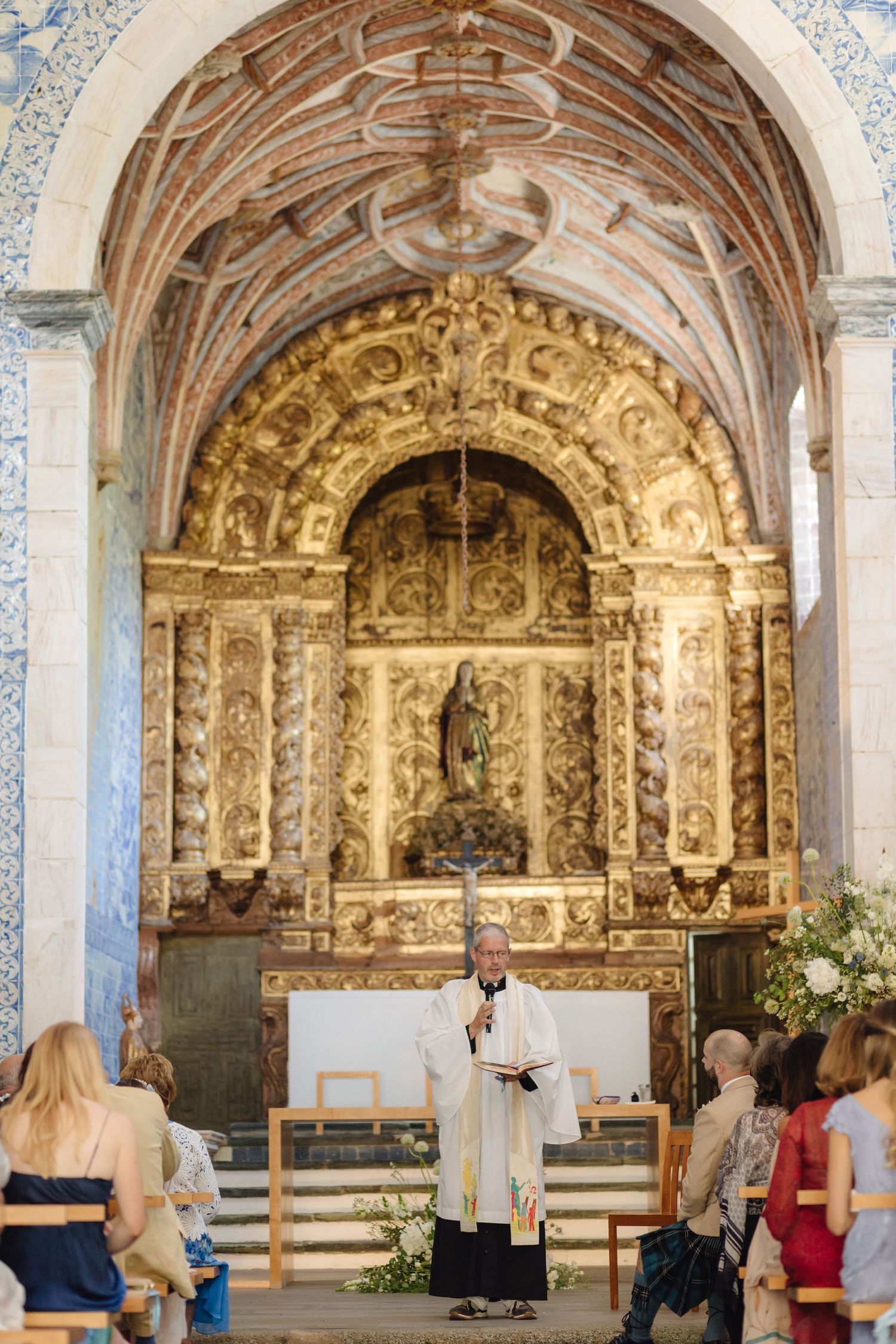 Ornate baroque church interior with gilded altar and blue and white tile walls during a wedding ceremony.
