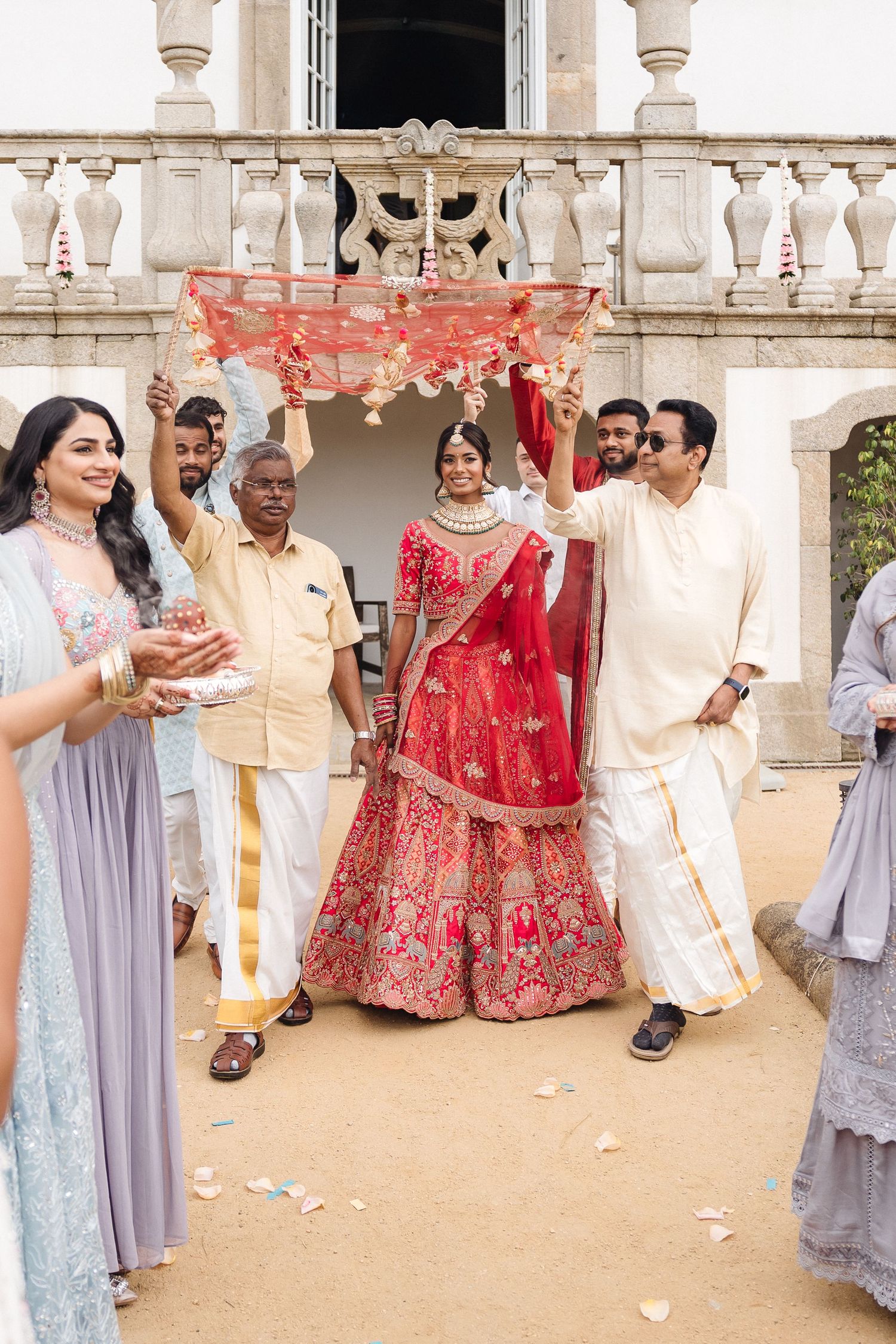 Traditional Indian wedding ceremony with guests in formal attire on ornate balcony.