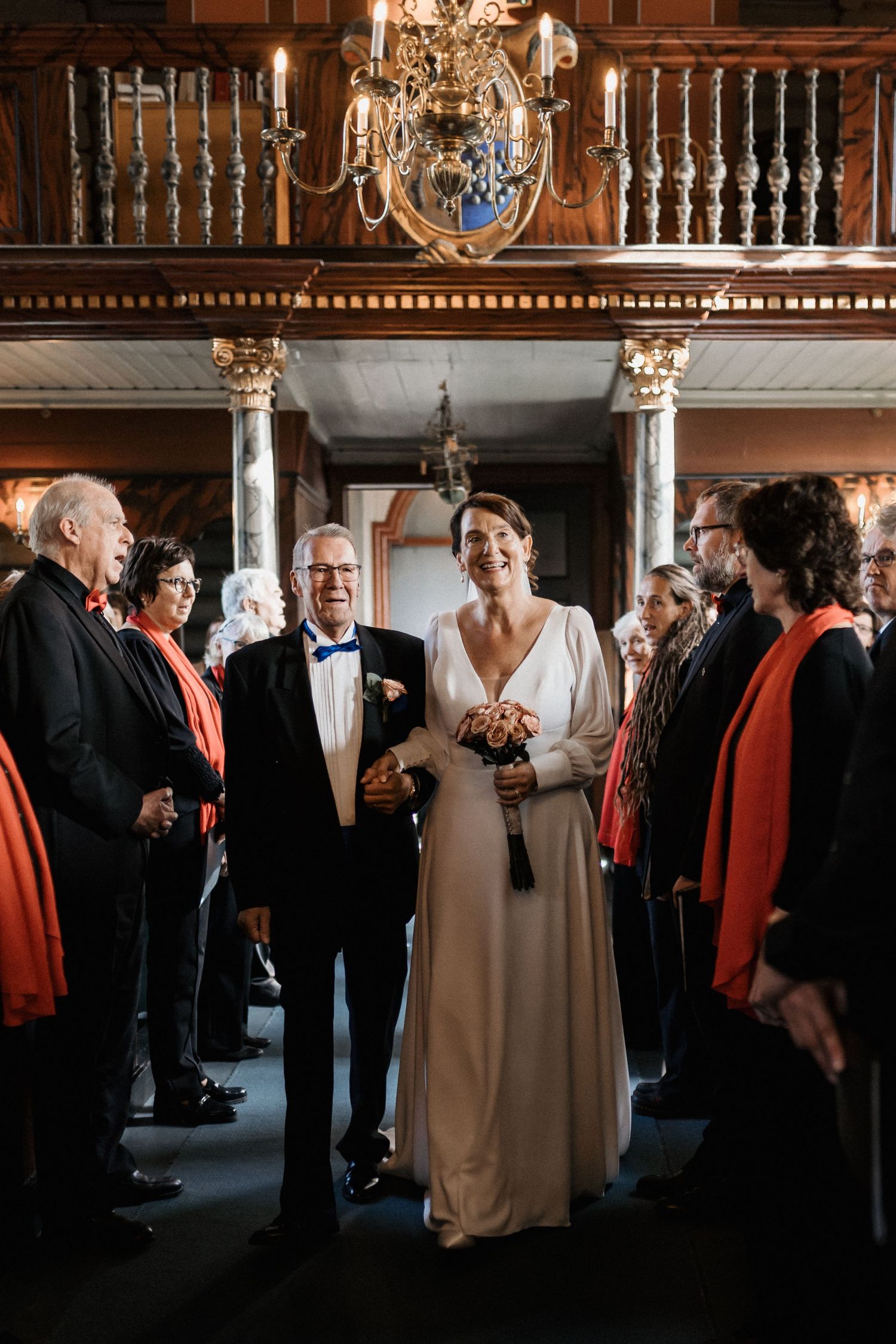 Elegant reception hall with chandeliers and guests mingling in formal attire.