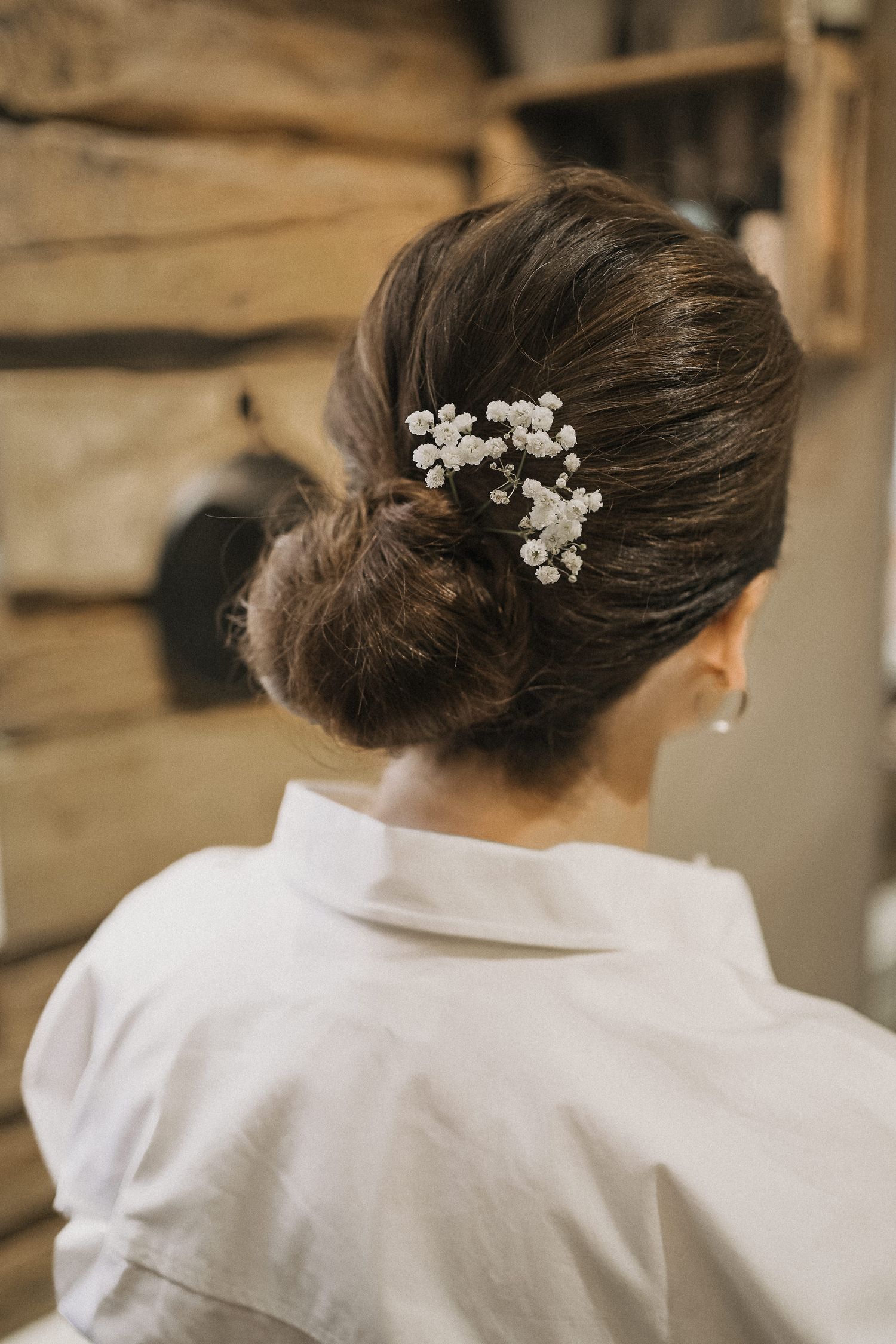 Back view of an elegant updo hairstyle with delicate white flowers woven into dark hair.