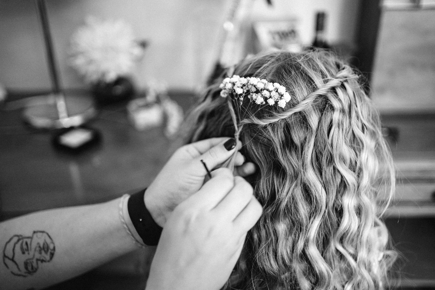 Close-up of intricate hairstyling with delicate floral accessories being placed.