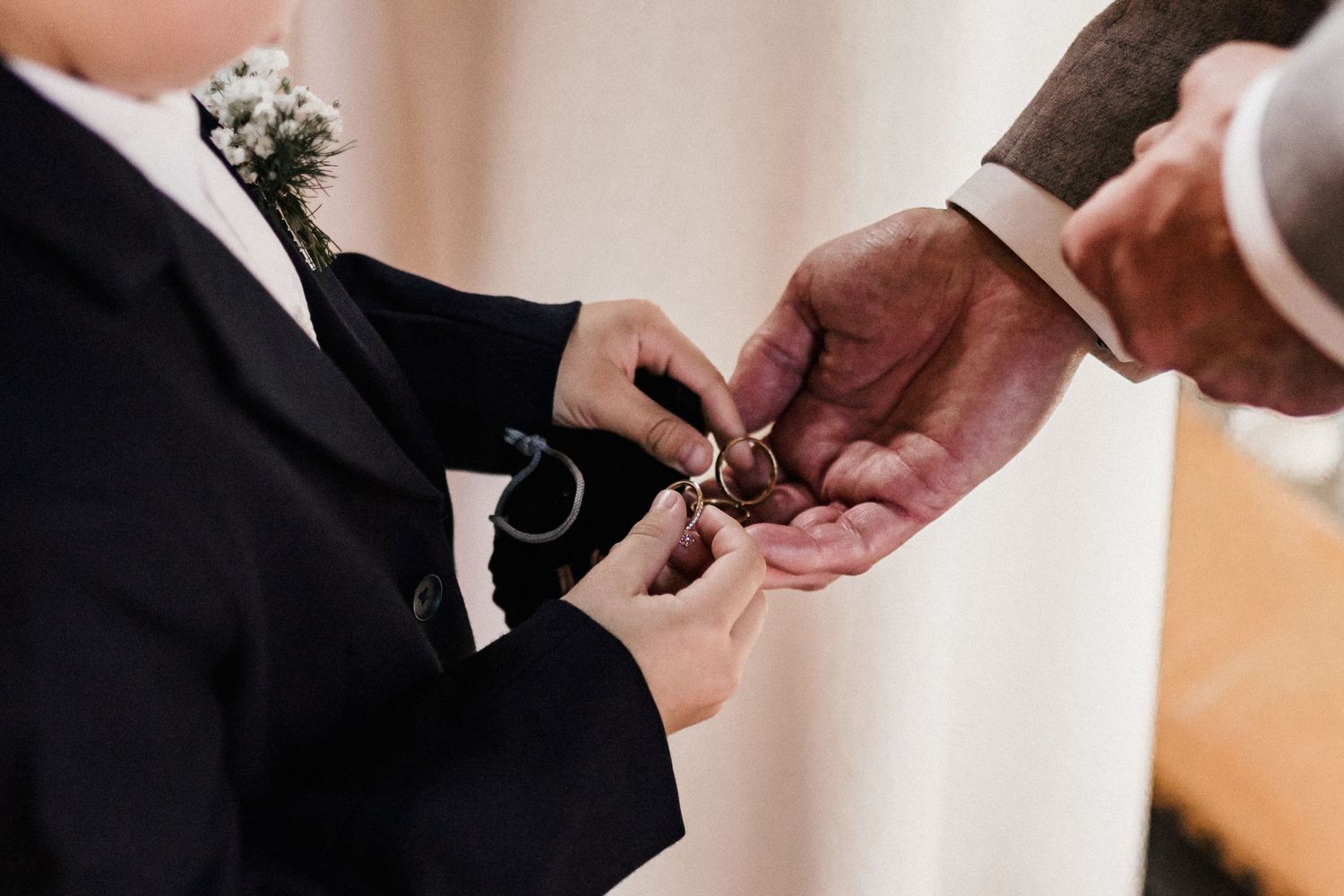 Close-up shots of hands exchanging rings during a wedding ceremony.