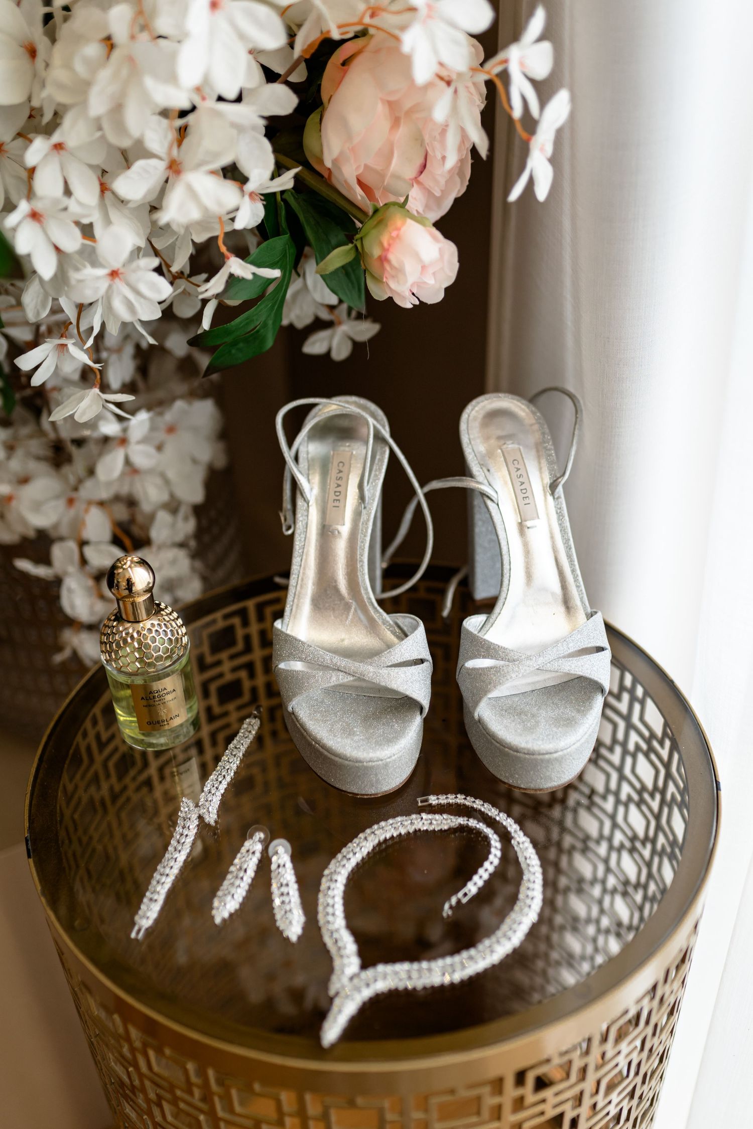 Wedding accessories including crystal heels and floral arrangements displayed on an ornate gold table.