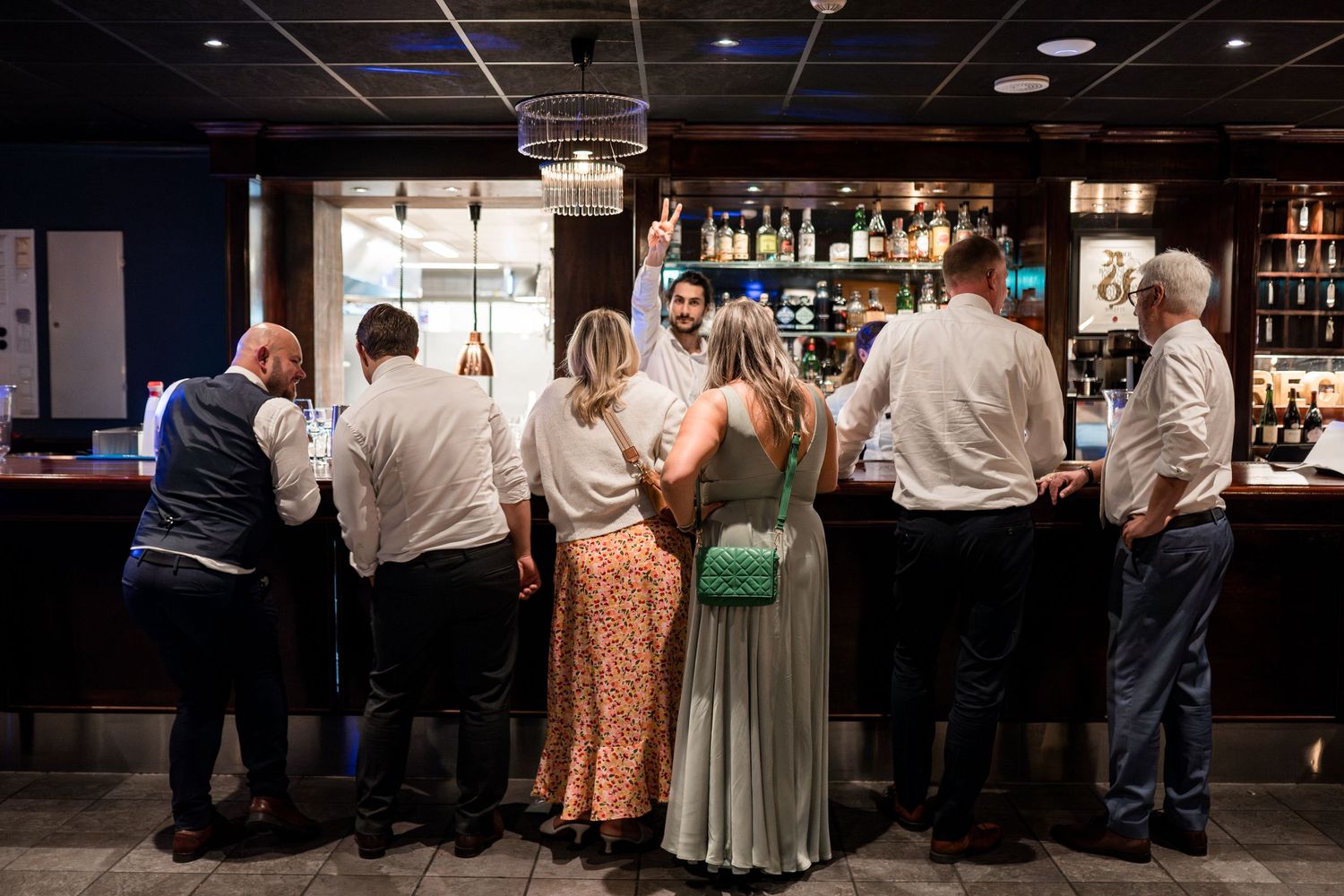 Wedding guests gathered around a dimly lit hotel bar area.