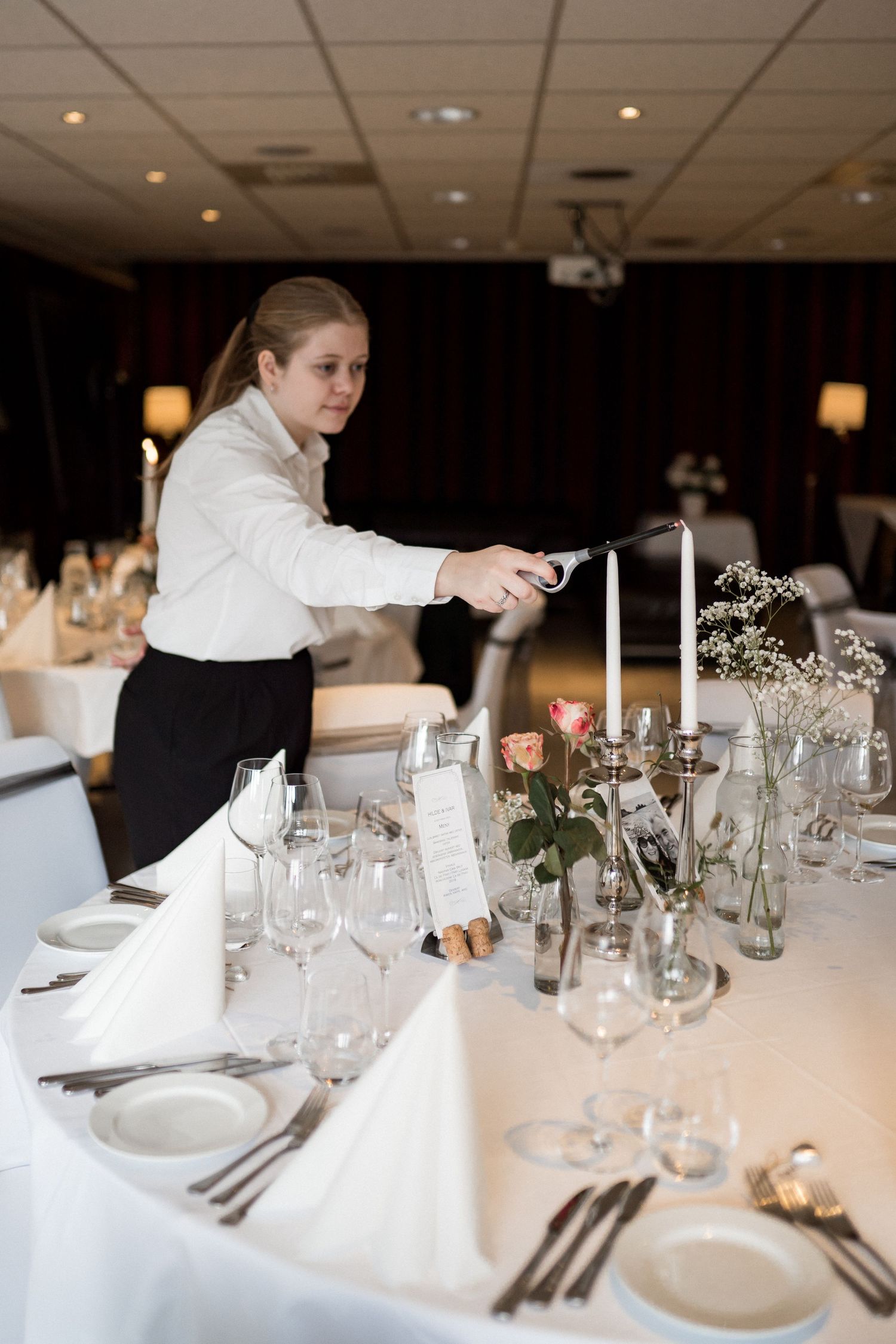 Elegant white wedding reception table settings with glassware, candles and simple floral centerpieces.