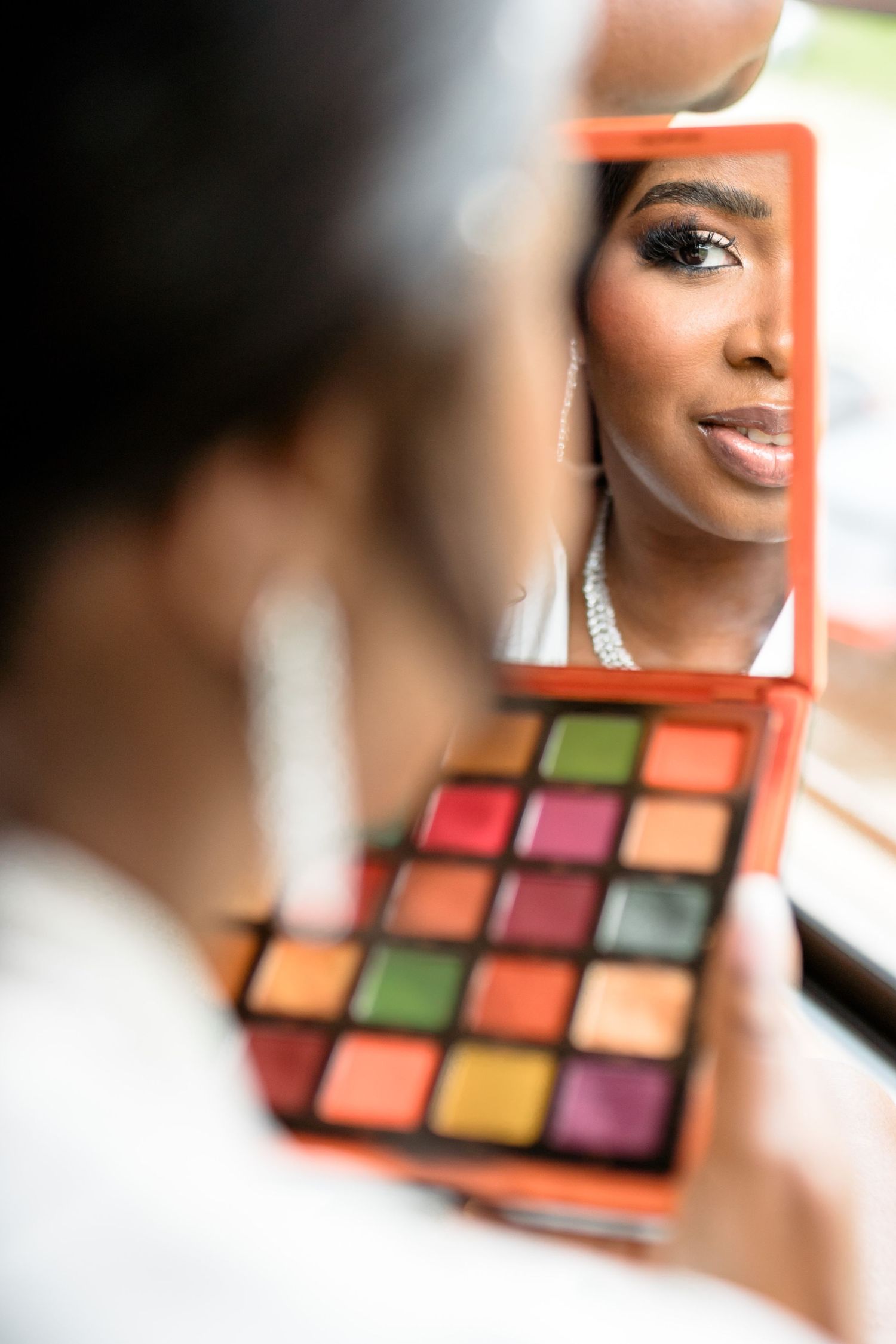 Colorful eyeshadow palette reflected in mirror showing vibrant makeup shades.
