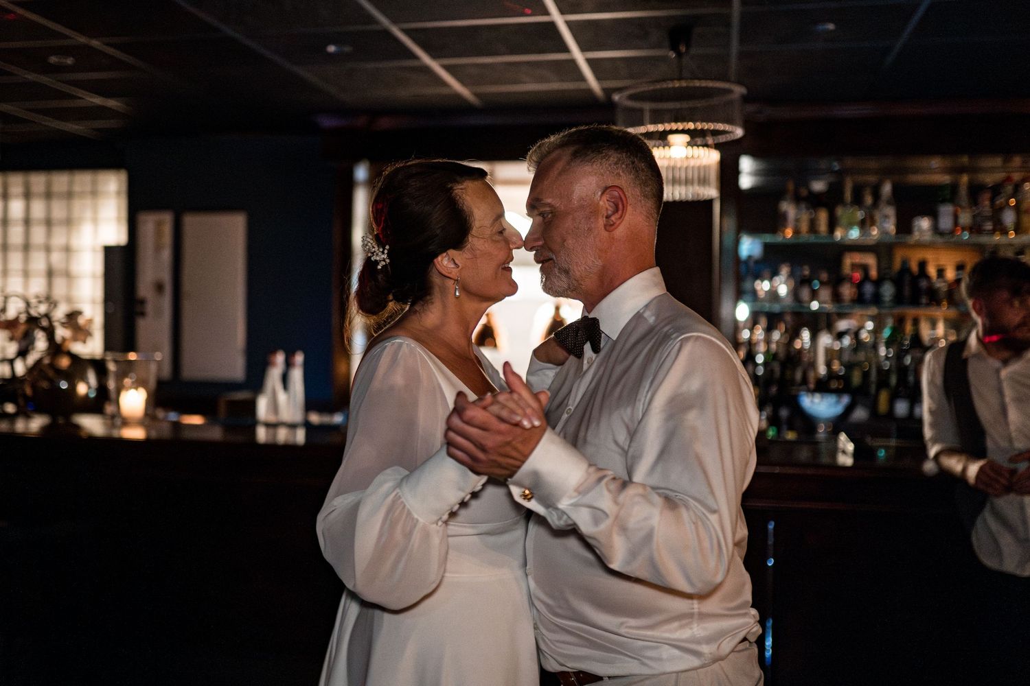 Couple sharing an intimate dance moment in a dimly lit bar setting.