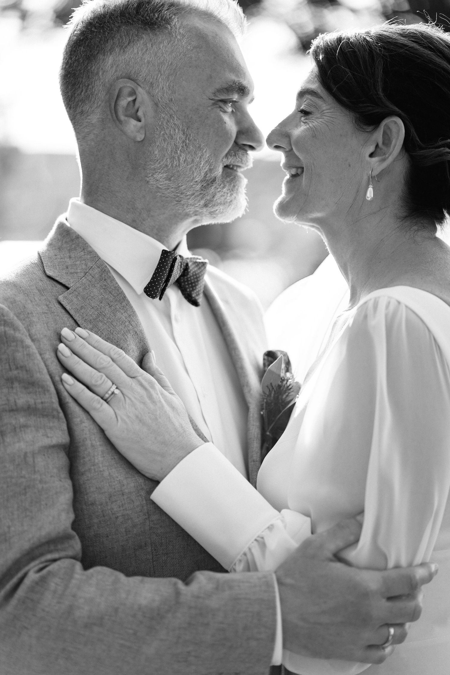 Black and white romantic wedding photos show tender moments between a couple in elegant attire.
