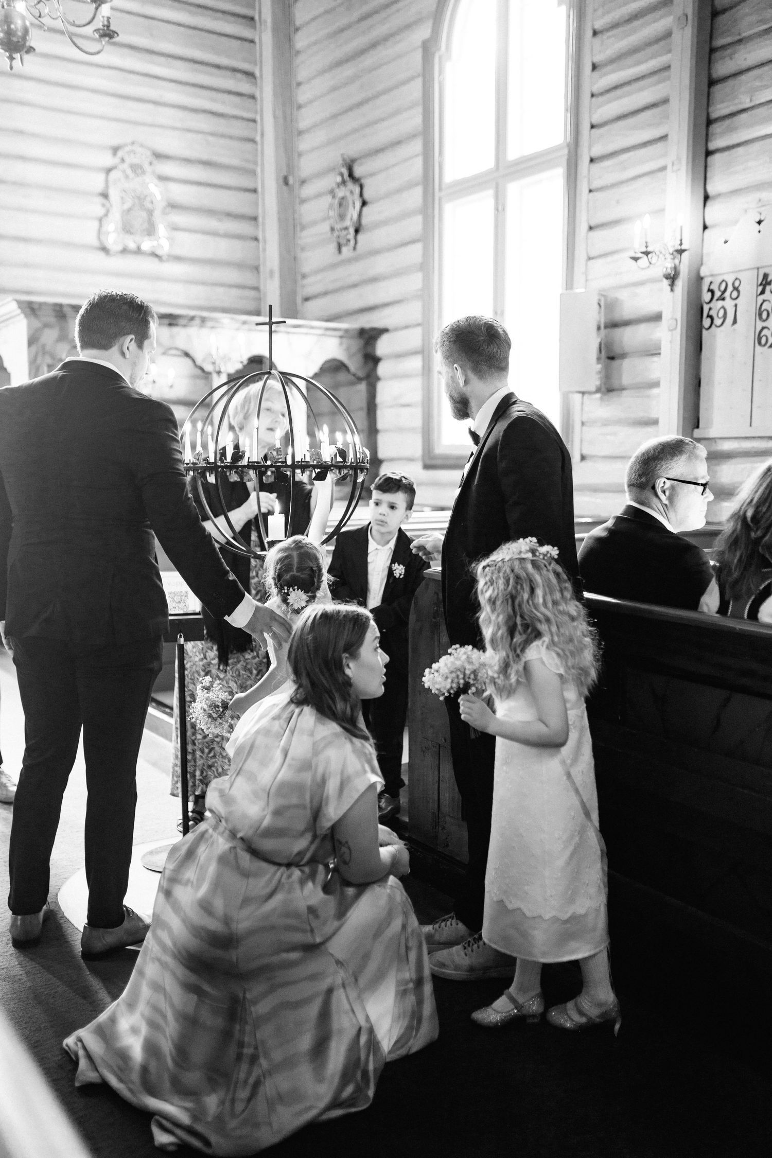 Children in formal attire standing among adults during a church wedding ceremony.
