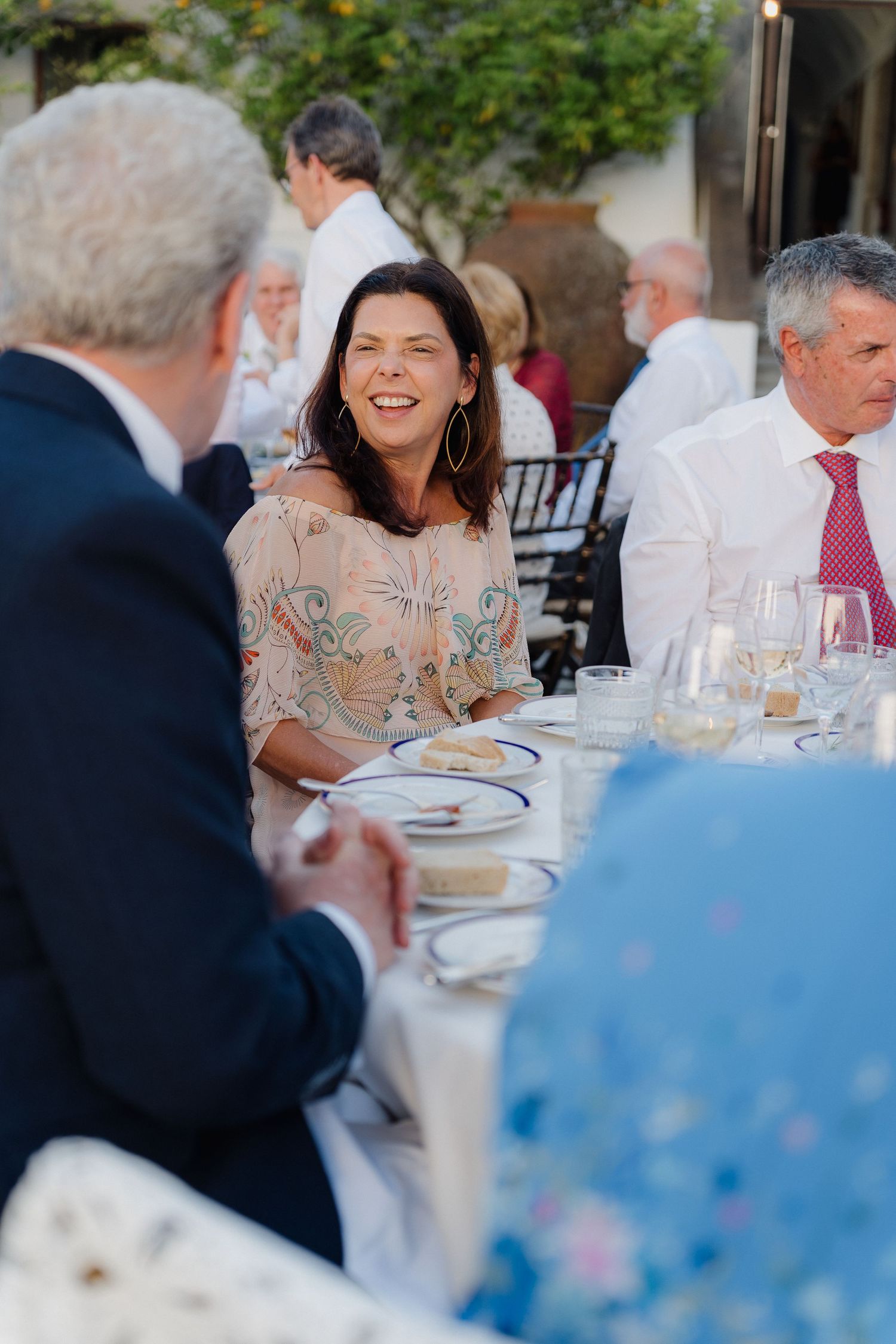 Guests sharing laughter during an outdoor dinner reception.
